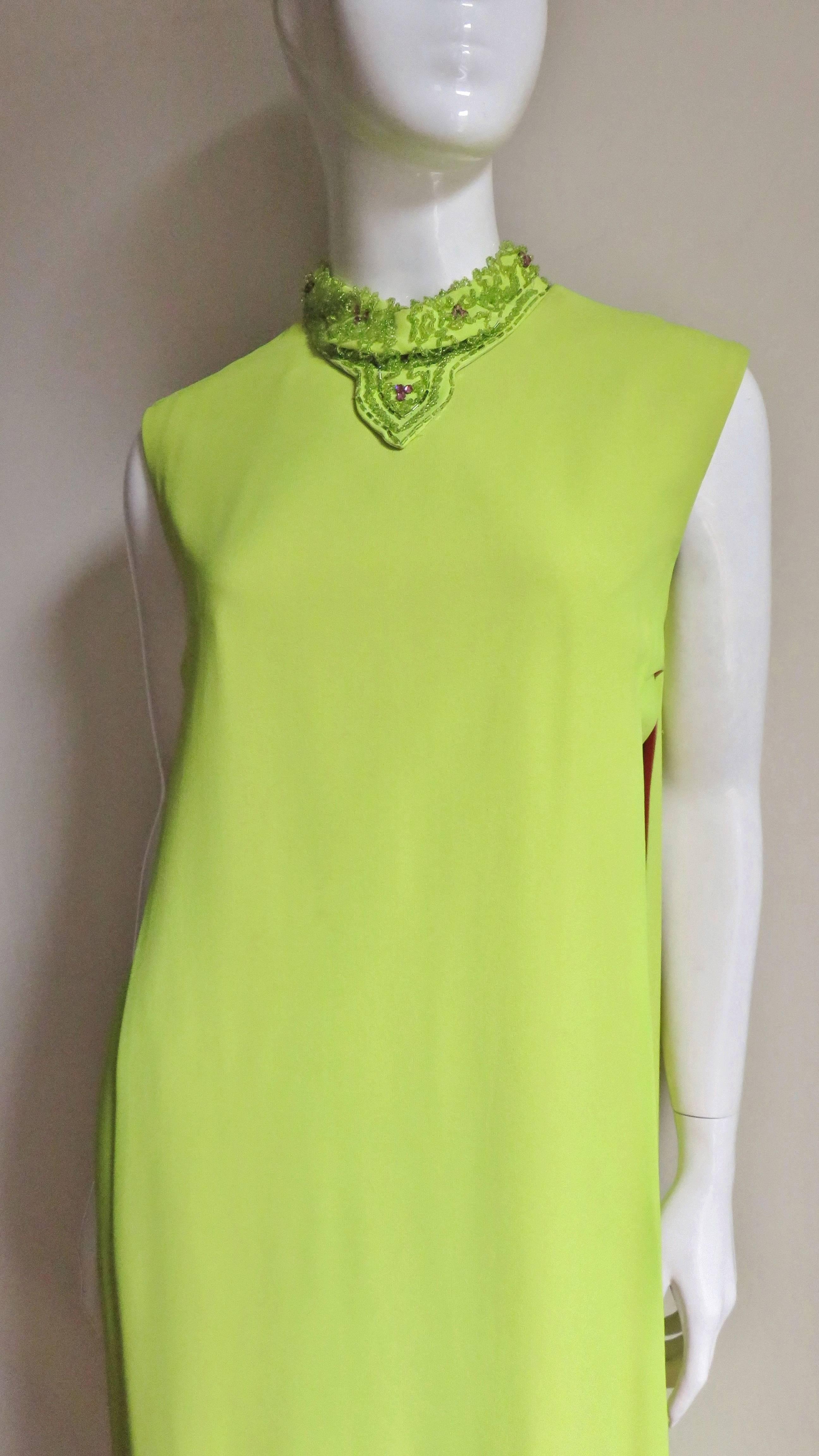 A fabulous maxi dress in bright yellow green and pink from Junior Vogue.  It is a semi fitted long sheath under a matching tabard overdress flashing the pink underneath it as it moves. The collar is highlighted with matching green glass beads and