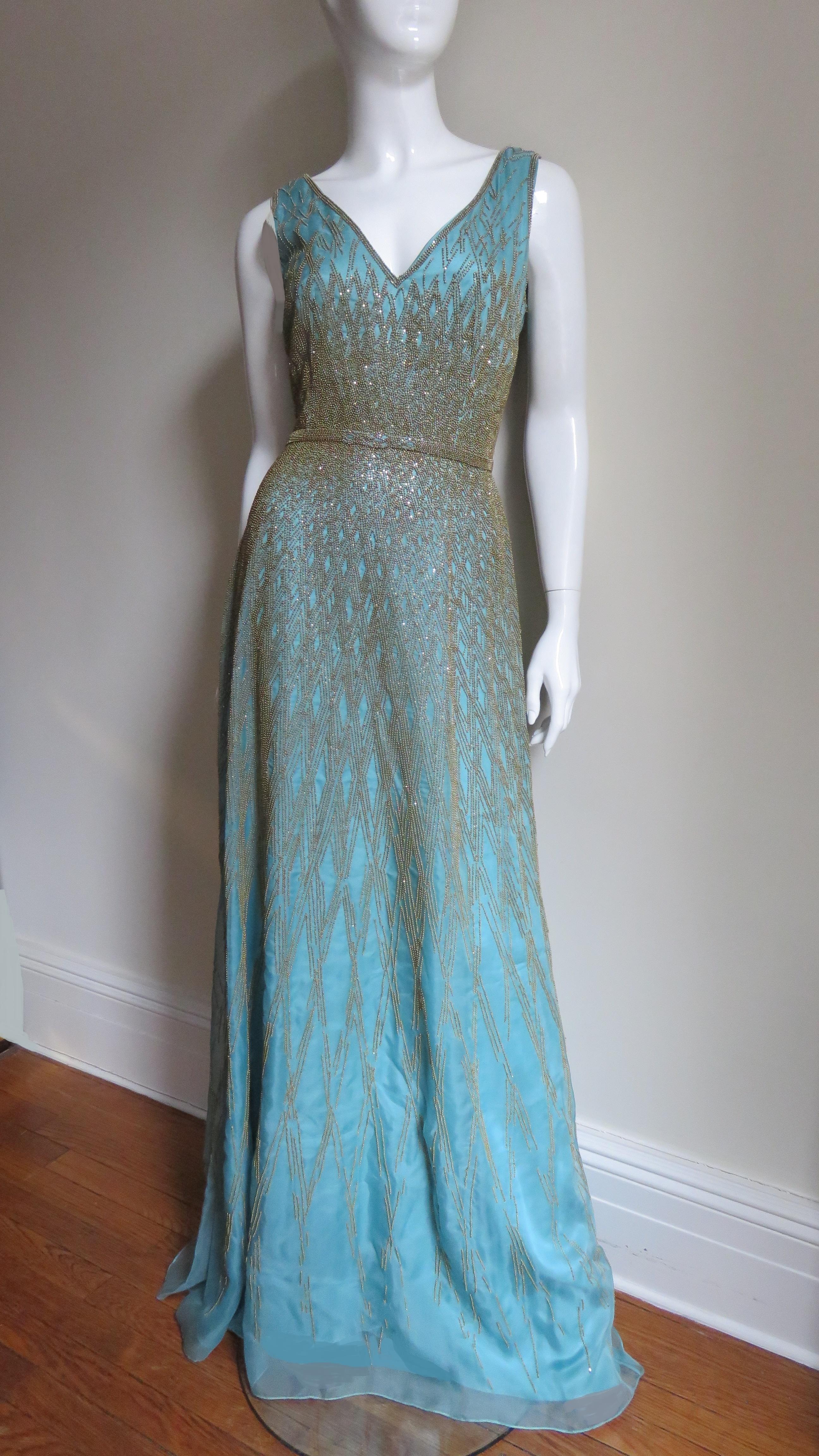 So gorgeous.. an aqua silk gown covered in an intricate design of gold glass beading by Carolina Herrera.  It has a V neckline, fitted waist and full skirt.  All are covered with a detailed pattern of gold beading on sheer aqua silk organza