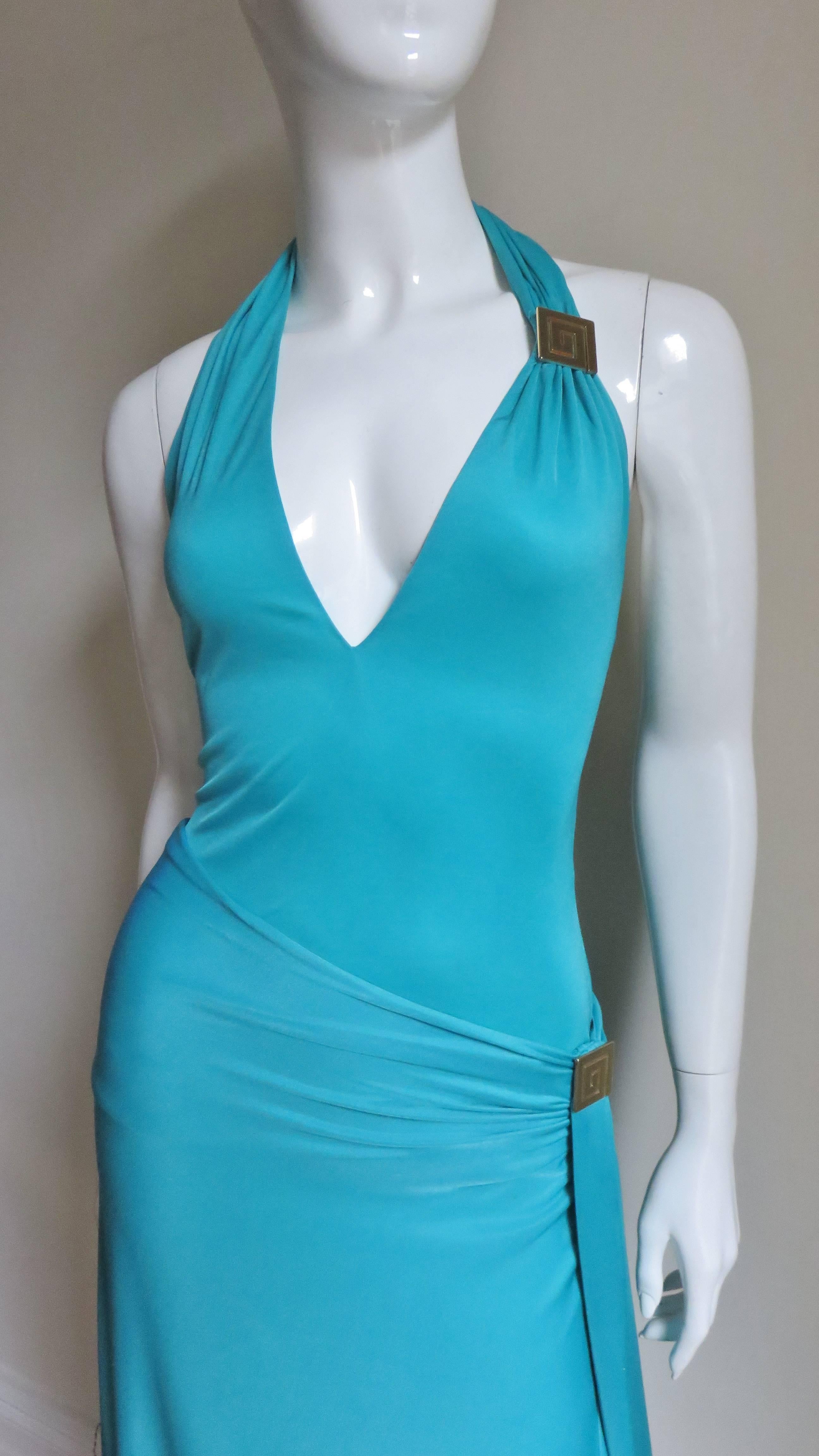 A fabulous turquoise silk jersey 2 piece halter dress from Gianni Versace.  The top has a plunging halter neckline.  The skirt drapes to the left side with a slit.  Both are adorned with a Versace insignia gold hardware Greek Keys, at the hip on one