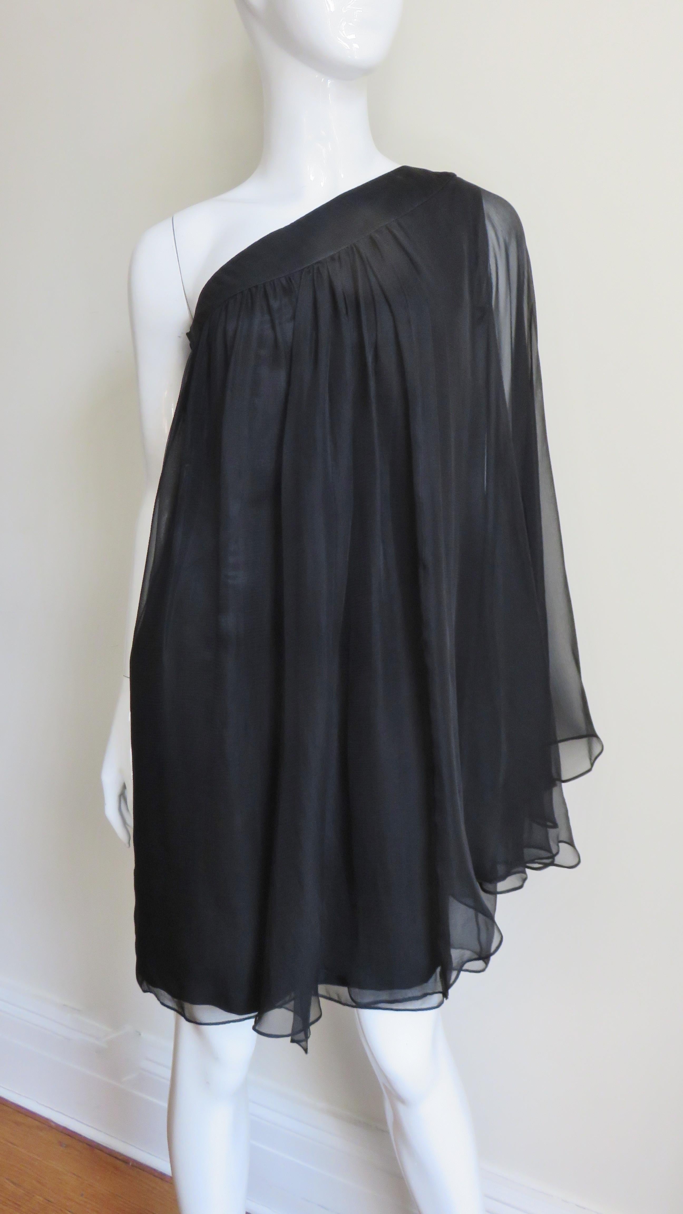 A beautiful and ethereal one shoulder dress from Christian Dior of layers of sheer black silk. Two panels of softly gathered folds of silk fall and overlap at the shoulder allowing the arm to peek out or be more exposed. Underneath is an attached