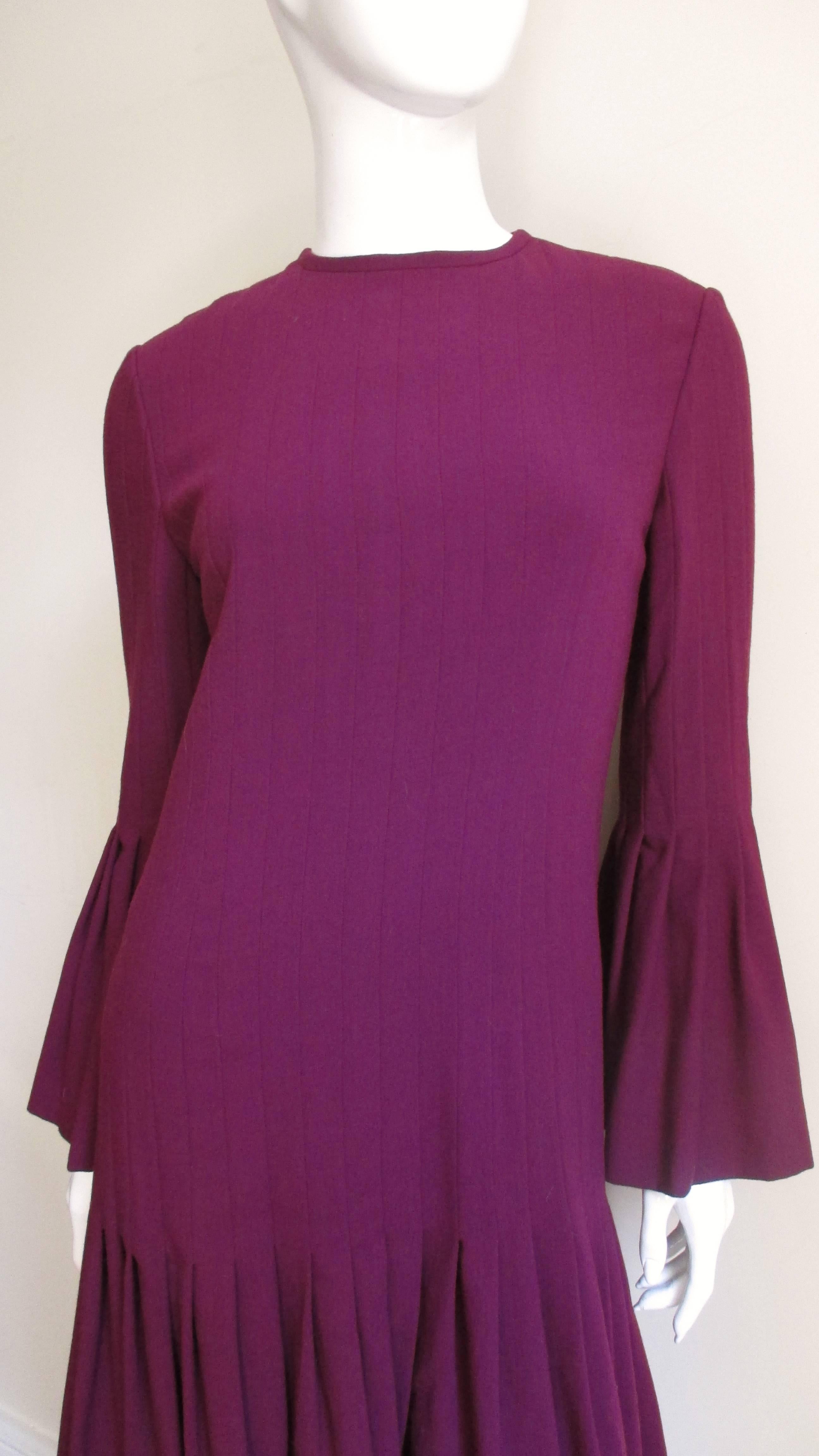 A beautiful wool dress from Pierre Cardin in burgundy wool crepe.  The body of the dress and the sleeves consist of vertical tucks which are released at the lower hips and on the sleeves just below the elbows.  This creates a flirty skirt from a