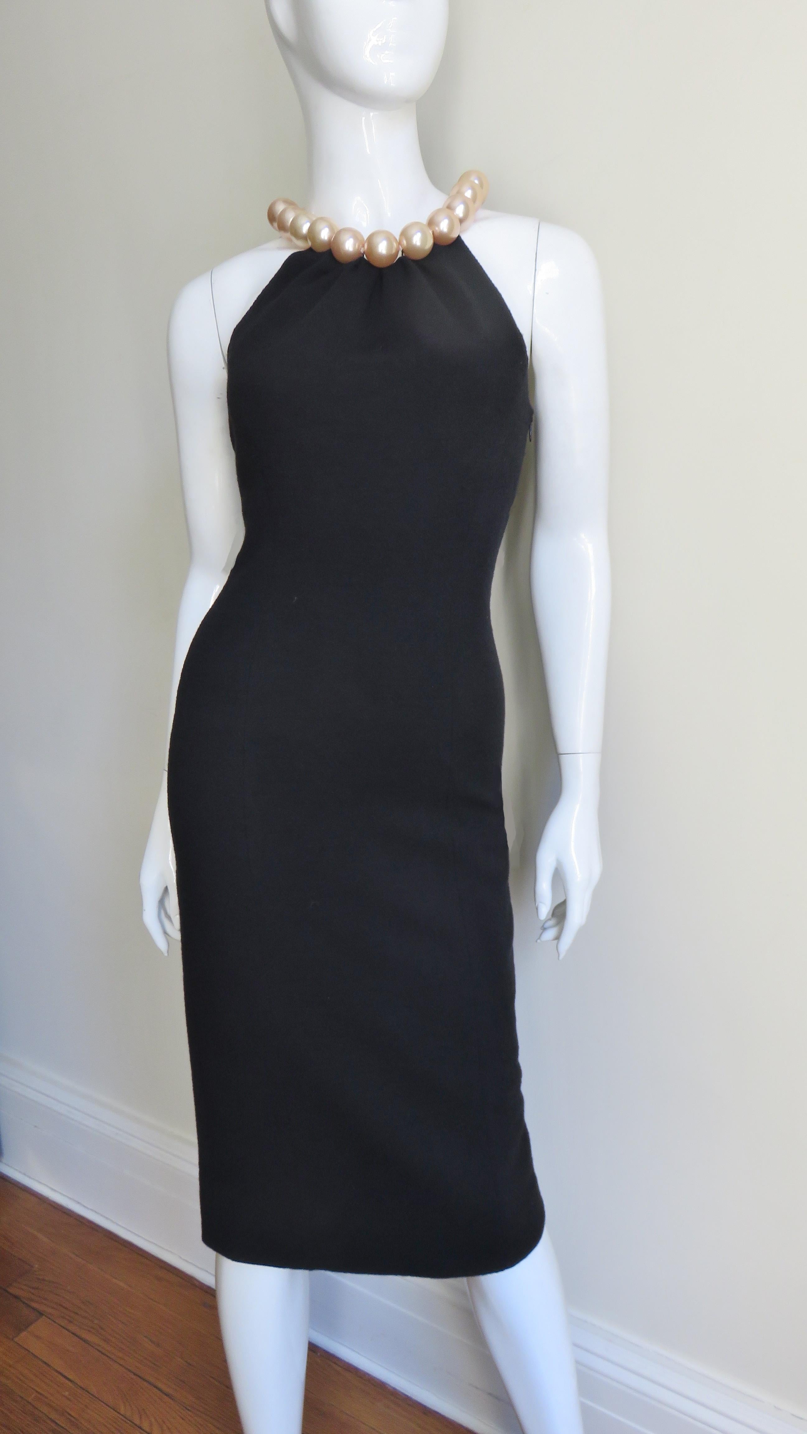 A fabulous fitted little black jersey dress from Moschino.  It has cut in shoulders and a large pearl necklace collar.  It is fully lined, has a slit at the center back hem, a side zipper and a spring ring closure at the back pearl necklace