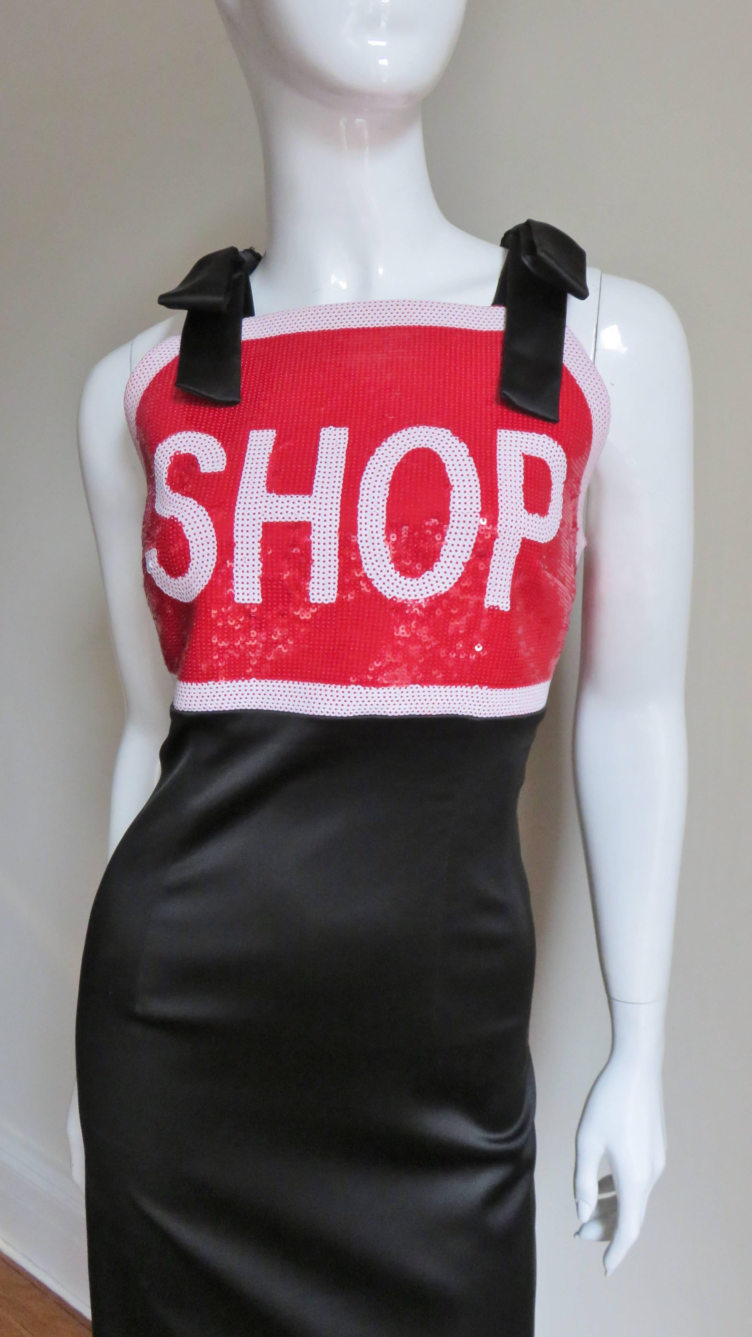 A fun dress in black, red and white by Jeremy Scott for Moschino Couture.  The front bodice portion is a play on a STOP sign consisting of white sequins with the word SHOP on a red sequin background.  It has black bow shoulder straps matching the
