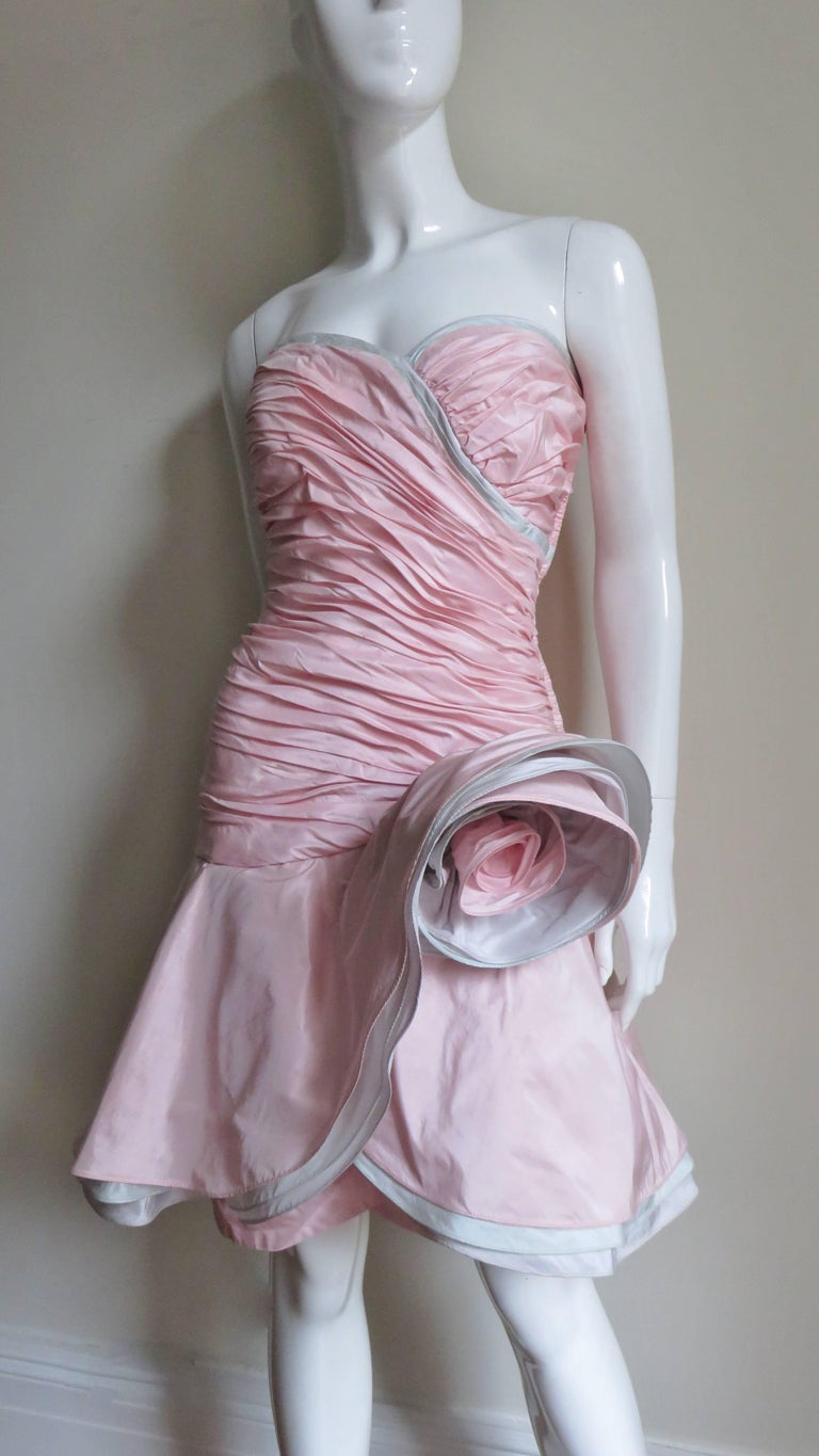 A fabulous bustier dress from Mignon in grey and pink silk.  It has a boned, ruched front crossing sweetheart cut strapless neckline piped on the edge in 2 shades of light grey.  A flirty full skirt consisting of three layers- 1 pink and 2 different