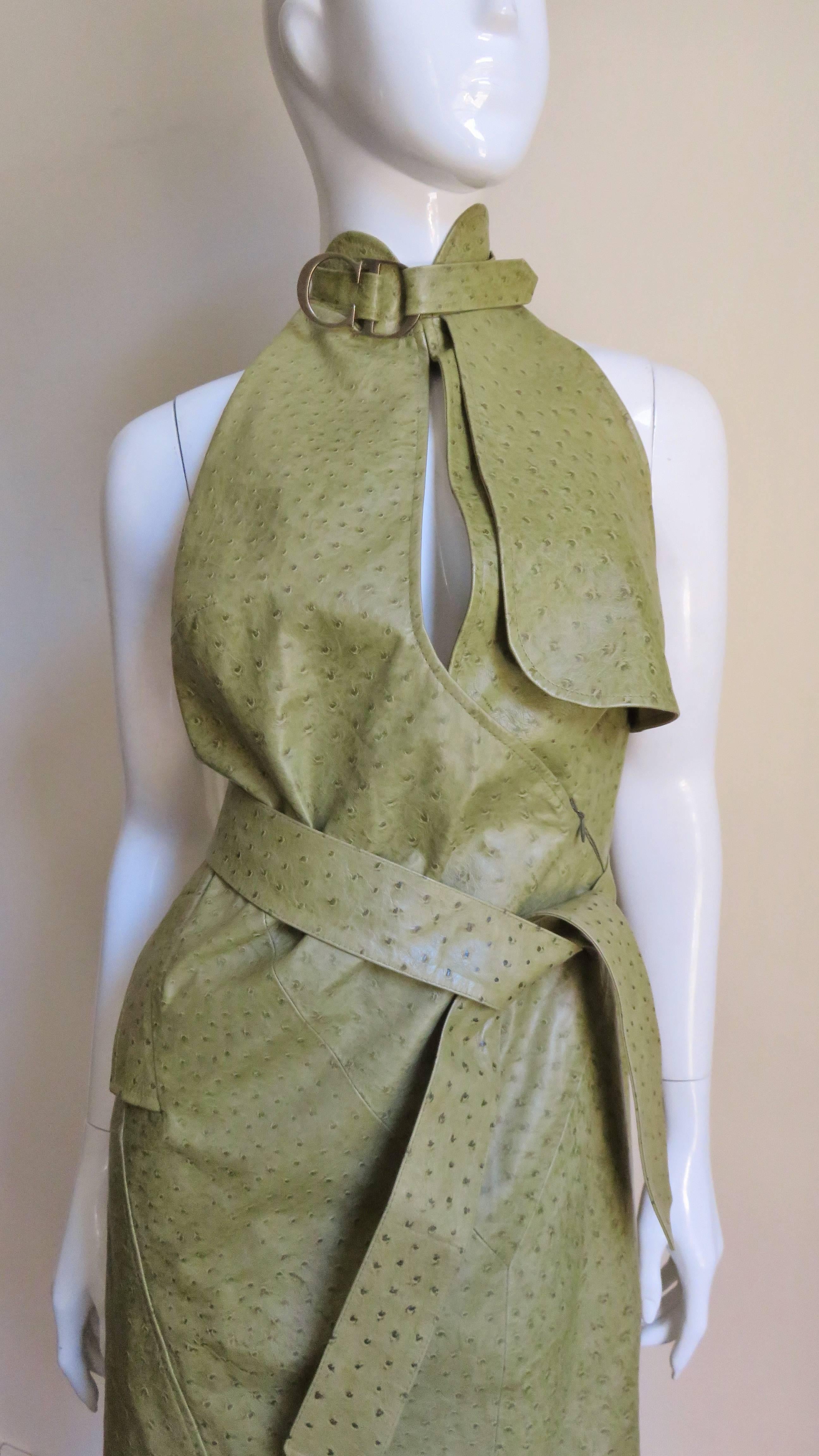 This is stunning!  It is an olive green ostrich halter dress from Christian Dior.  It closes at the neck with a strap at the stand up collar with the letters CD in burnished brass and a plunging keyhole neckline. The bodice wraps and zips closed.