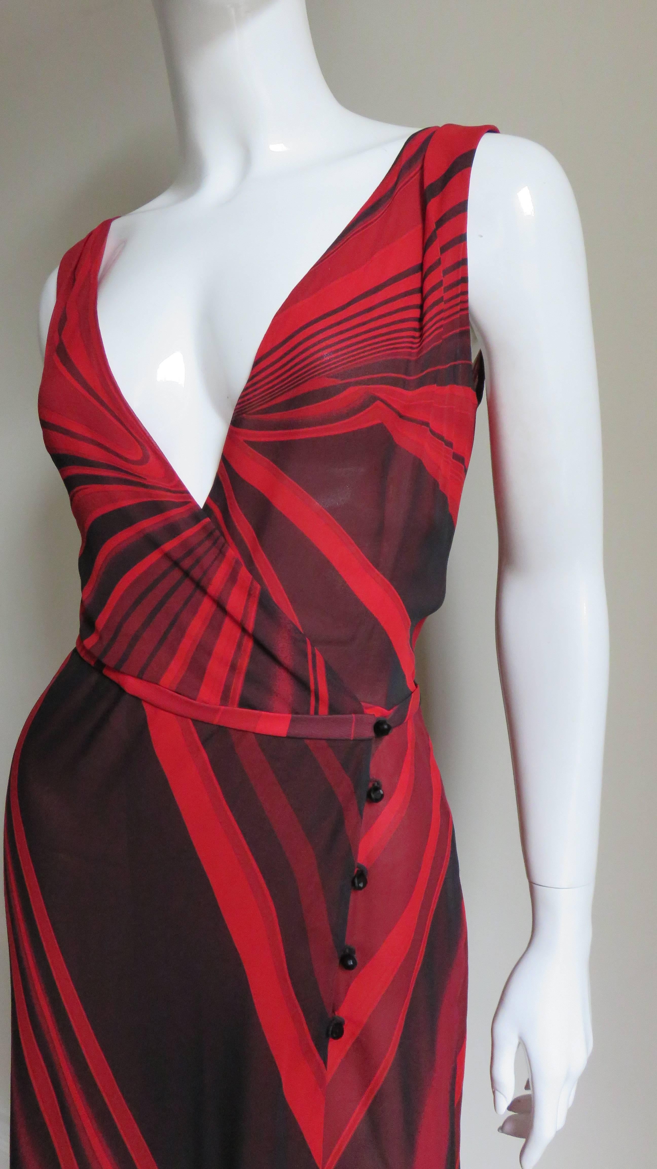 A great red and black abstract patterned silk dress by Gianni Versace Couture.  It has a plunging neckline wrapping at the waist closing with inner snaps and 5 black faceted glass buttons and loops along one side.  There is a center back gore in the