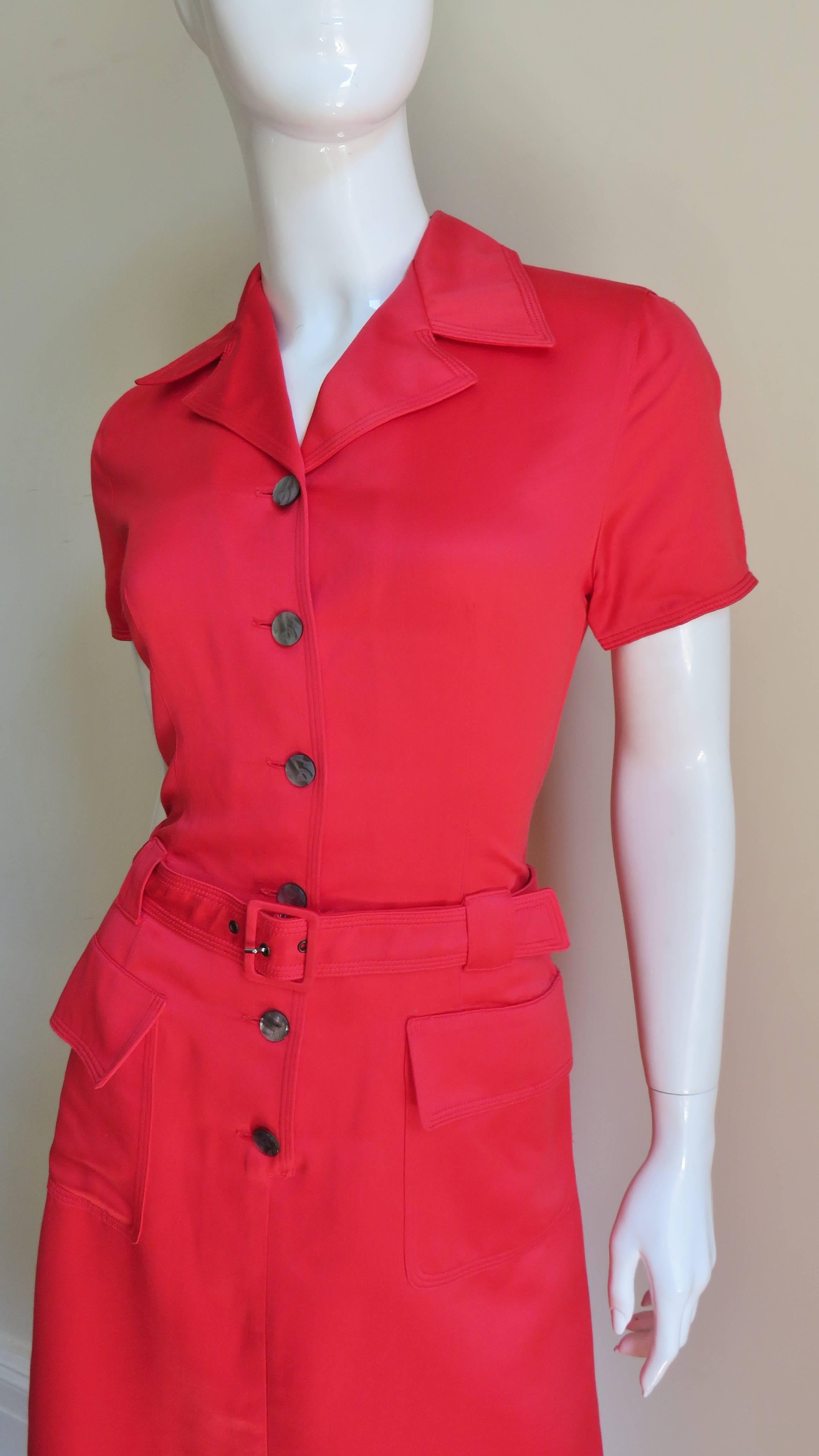 A great little red cotton blend dress from Salvatore Ferragamo.  It has a lapel collar, short sleeves, 2 front patch flap pockets and a belted waist all finished with rows of top stitching.   It closes up the front with grey mother of pearl buttons