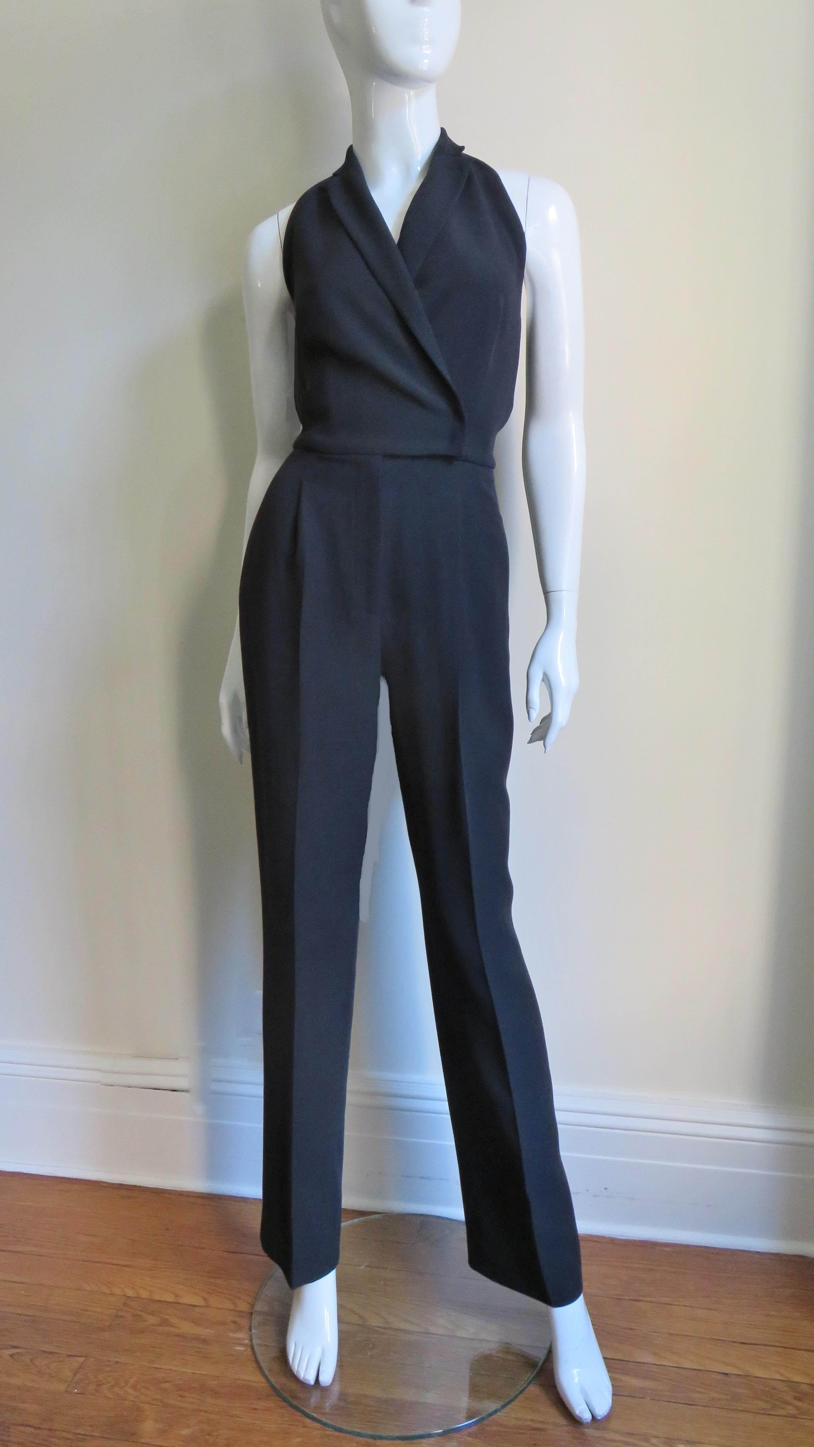 A great black silk halter jumpsuit from Valentino  The front bodice wraps and has small notched lapels.  The waist is fitted and the pants portion have hip seam pockets and a center front fly zipper closing.  It is unlined and has snap closures at