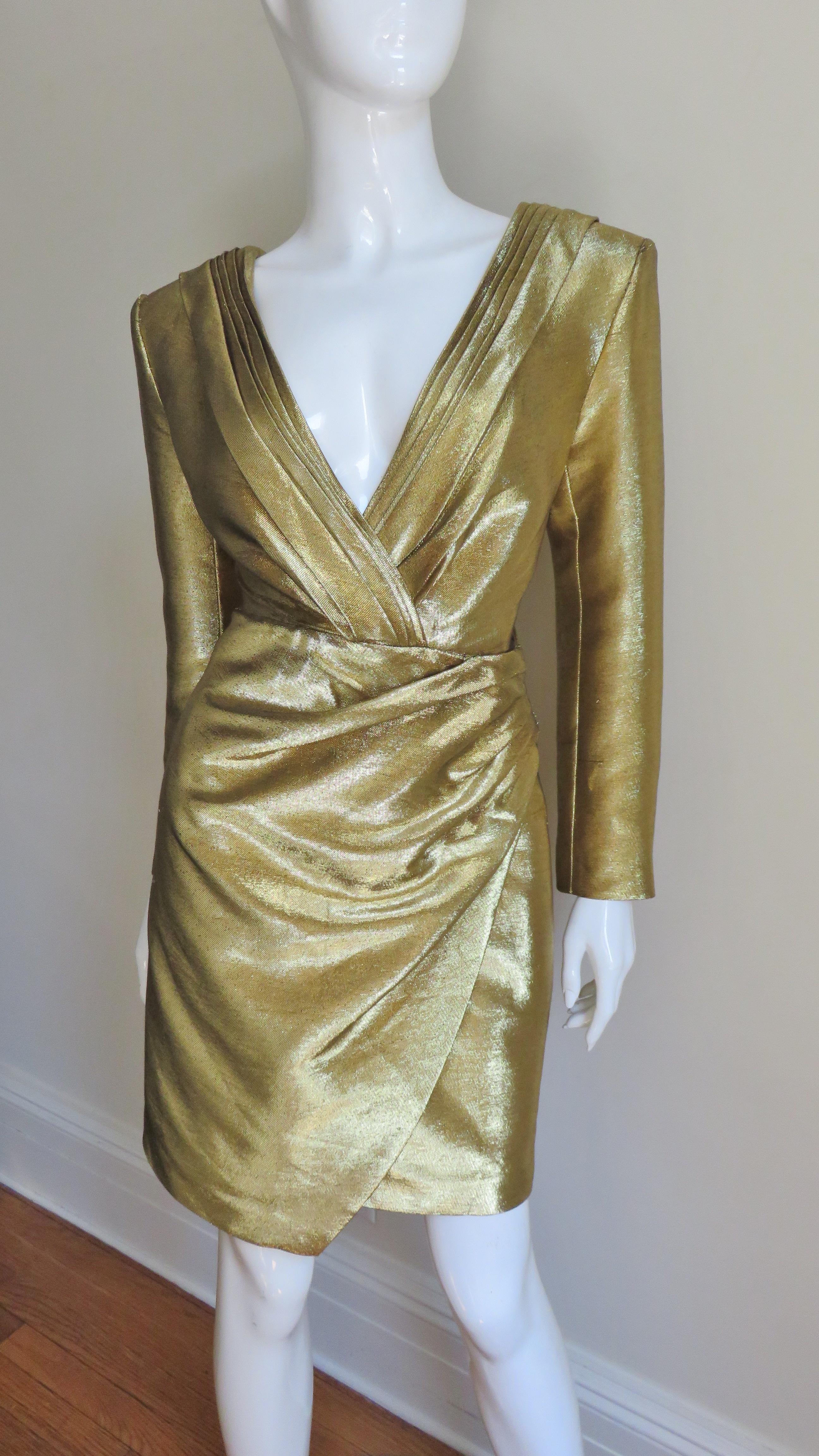 An incredible gold lame plunge front dress from Saint Laurent. It has a plunging front and back neckline framed in folds of the gold fabric crossing at the center front and back.  The skirt is softly draping and folds over one side at an angle. 