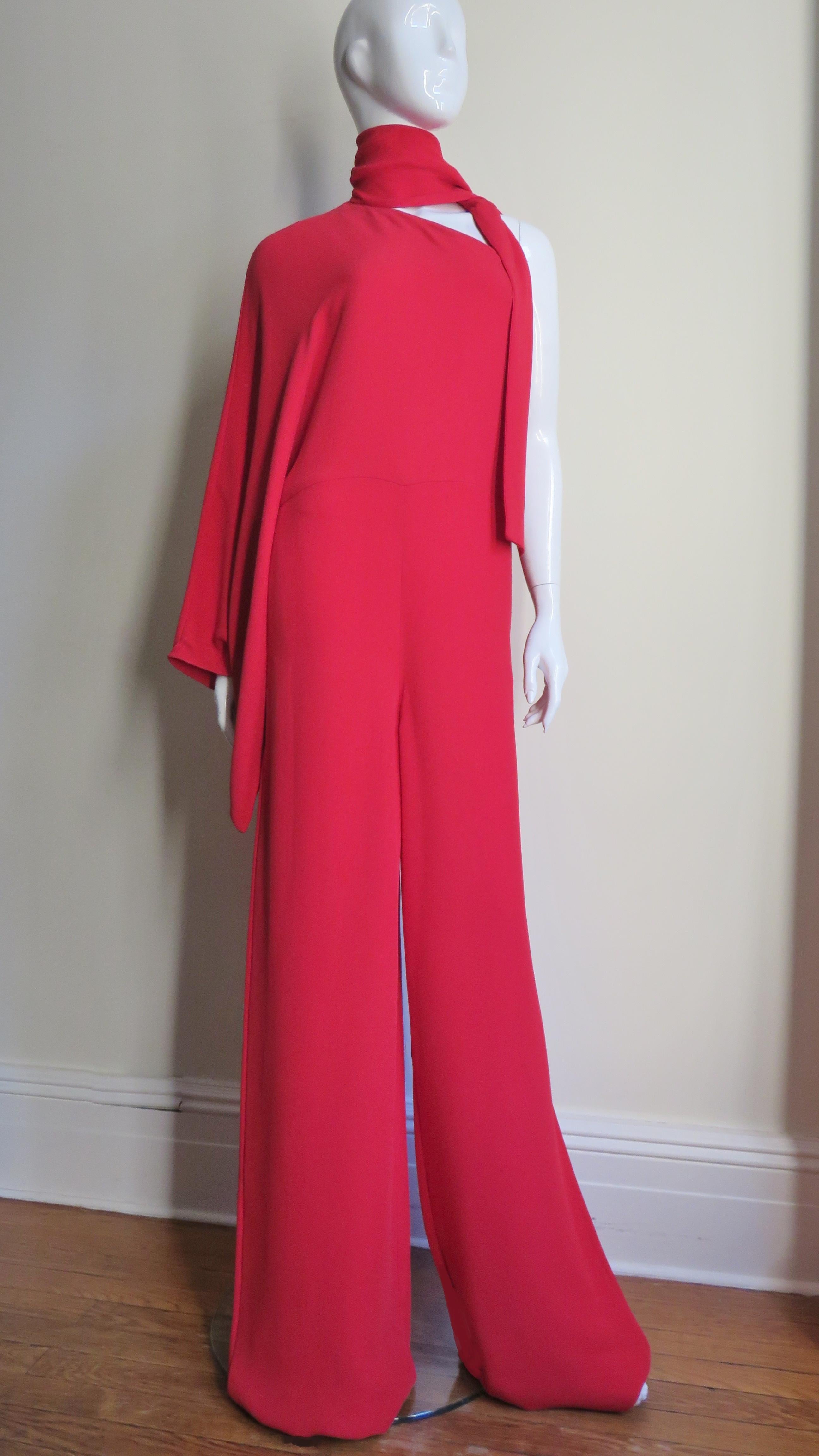 This is an incredible rich red silk jumpsuit from Valentino.  It has one kimono style sleeve to the waist seam open hand width at the wrist and a tie at the neck.  The torso is nipped in at the waist where there is a seam and the legs are wide.  It