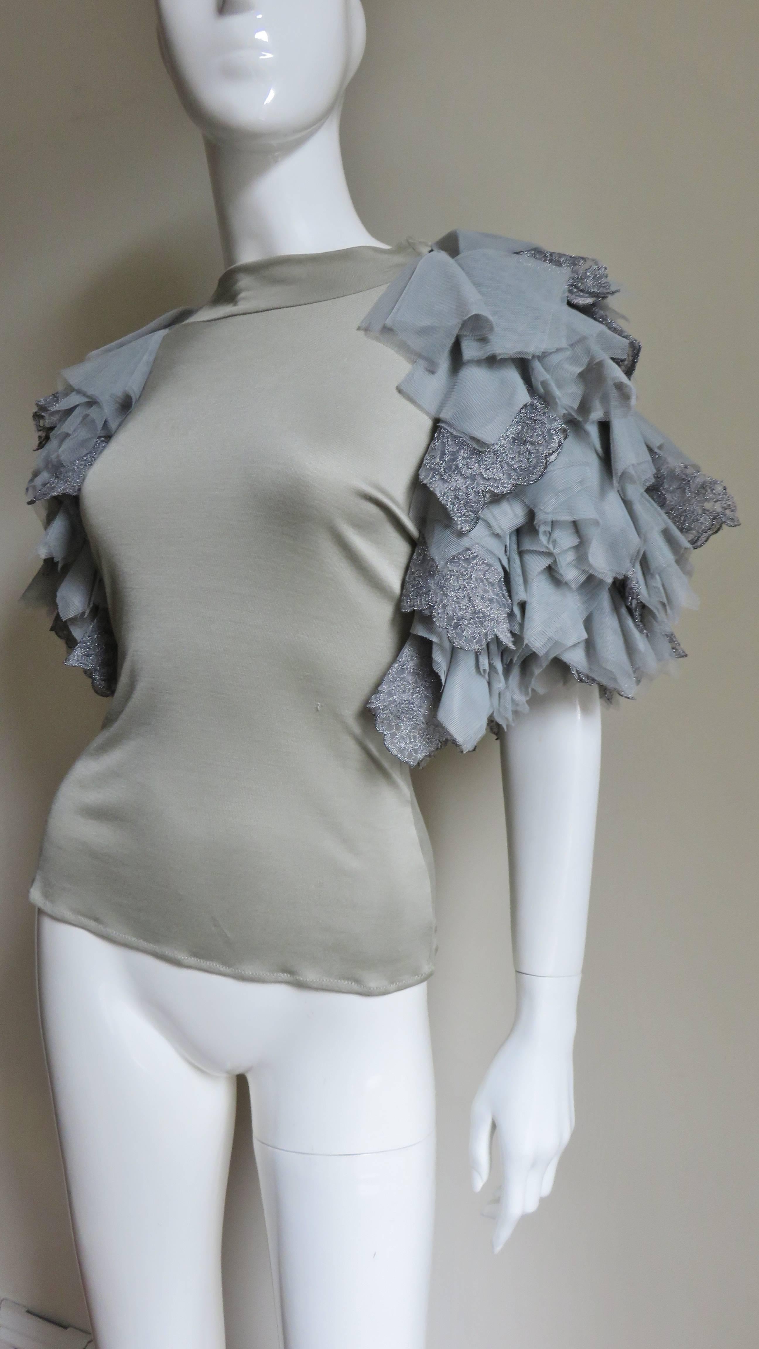 An incredible grey fine knit silk t-shirt from Alexander McQueen.  It has a crew neckline and the most elaborate grey net, tulle and lace appliqued layered sleeves.
Unworn condition.  Fits sizes small, Medium.

Bust  35-38