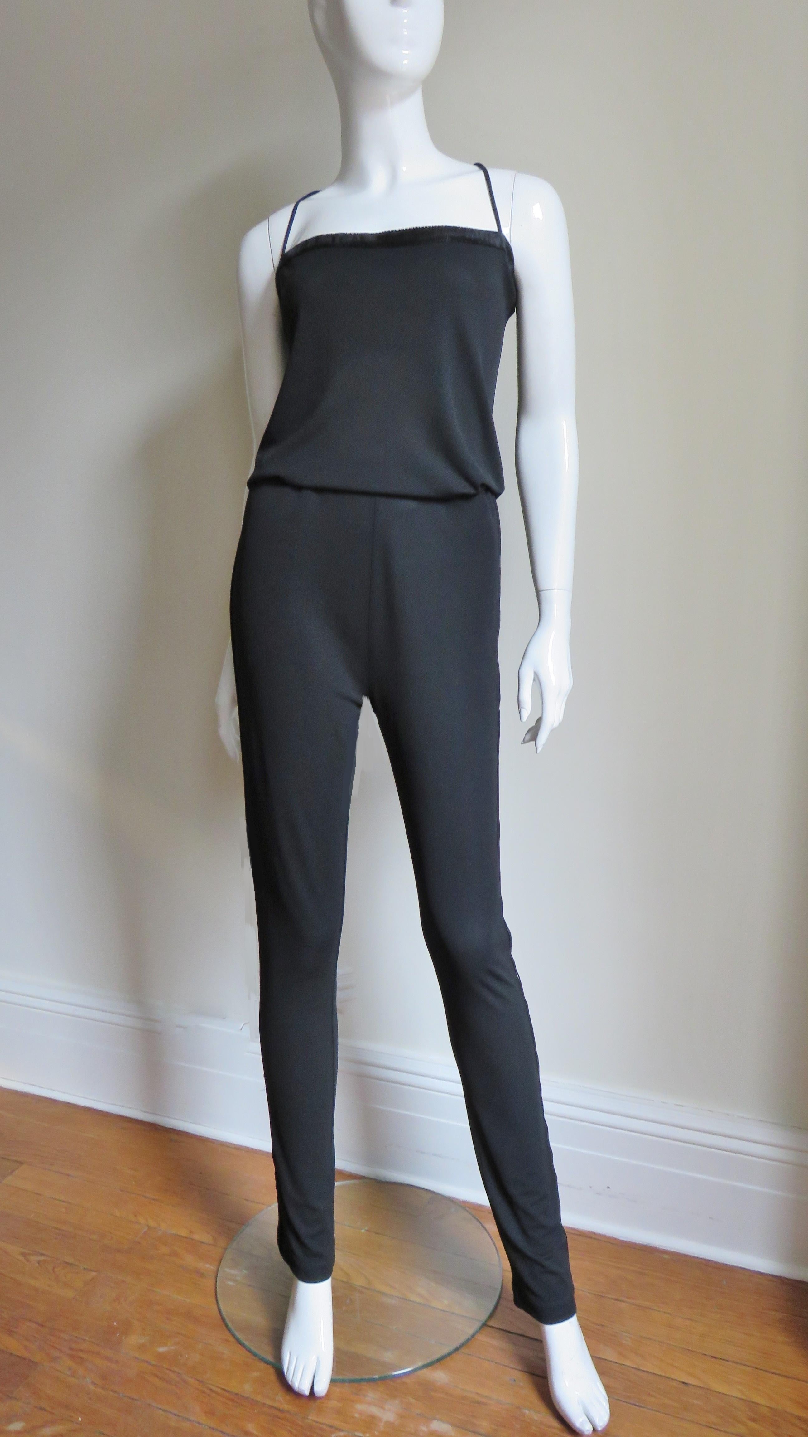 A beautiful new black silk jersey Gucci Jumpsuit.  It is straight across above the bust with adjustable spaghetti straps criss crossing above back draping. The top of the bust and the side of the pant legs have a strip of  fine velvet.  There are