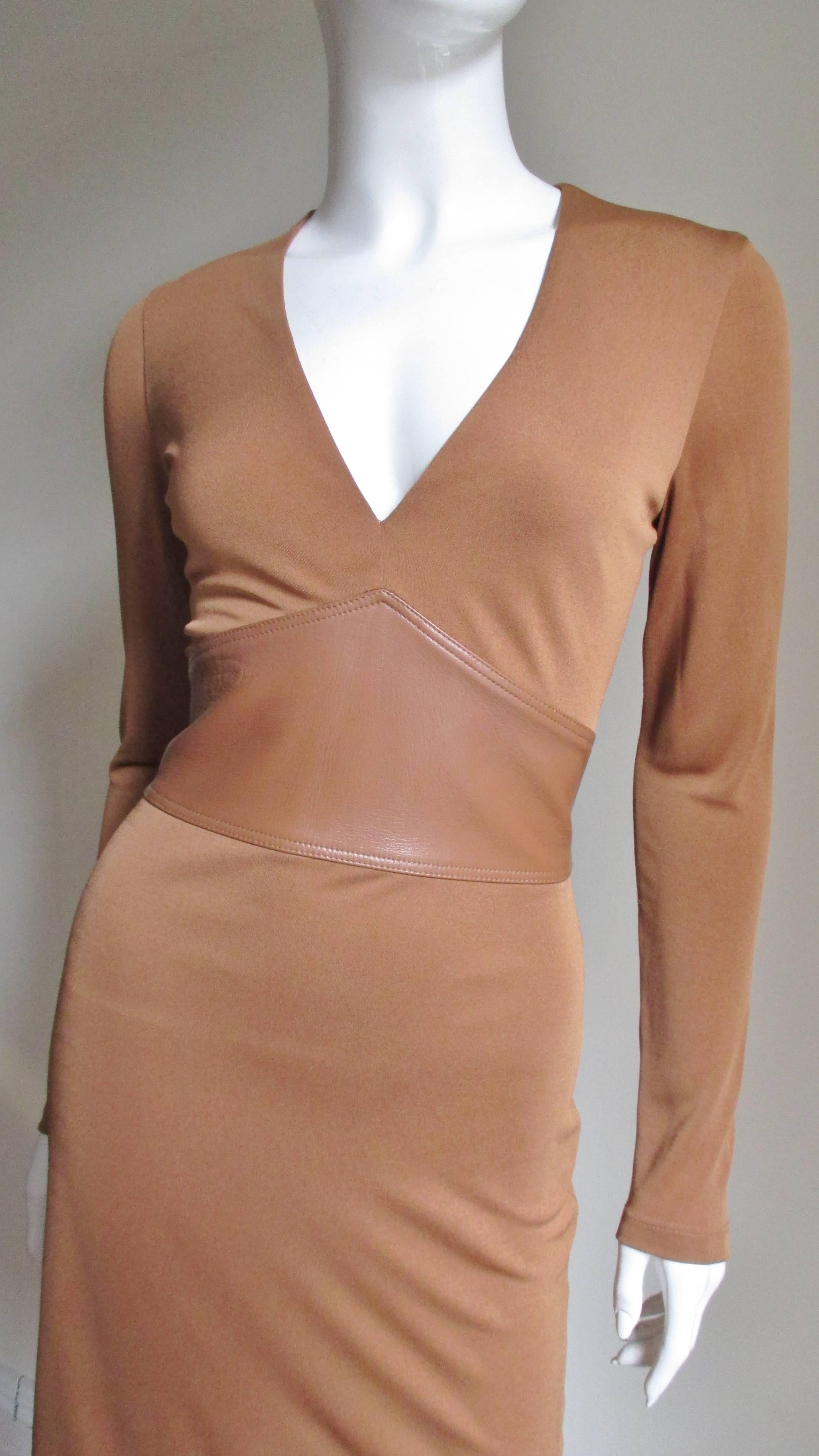 A stunning silk jersey dress from Gianni Versace Couture in a gorgeous caramel tan color. It has a plunging neckline and a wide matching leather inset waist. The skirt is straight, the dress is lined in the same fabric and has a back zipper.  
Fits