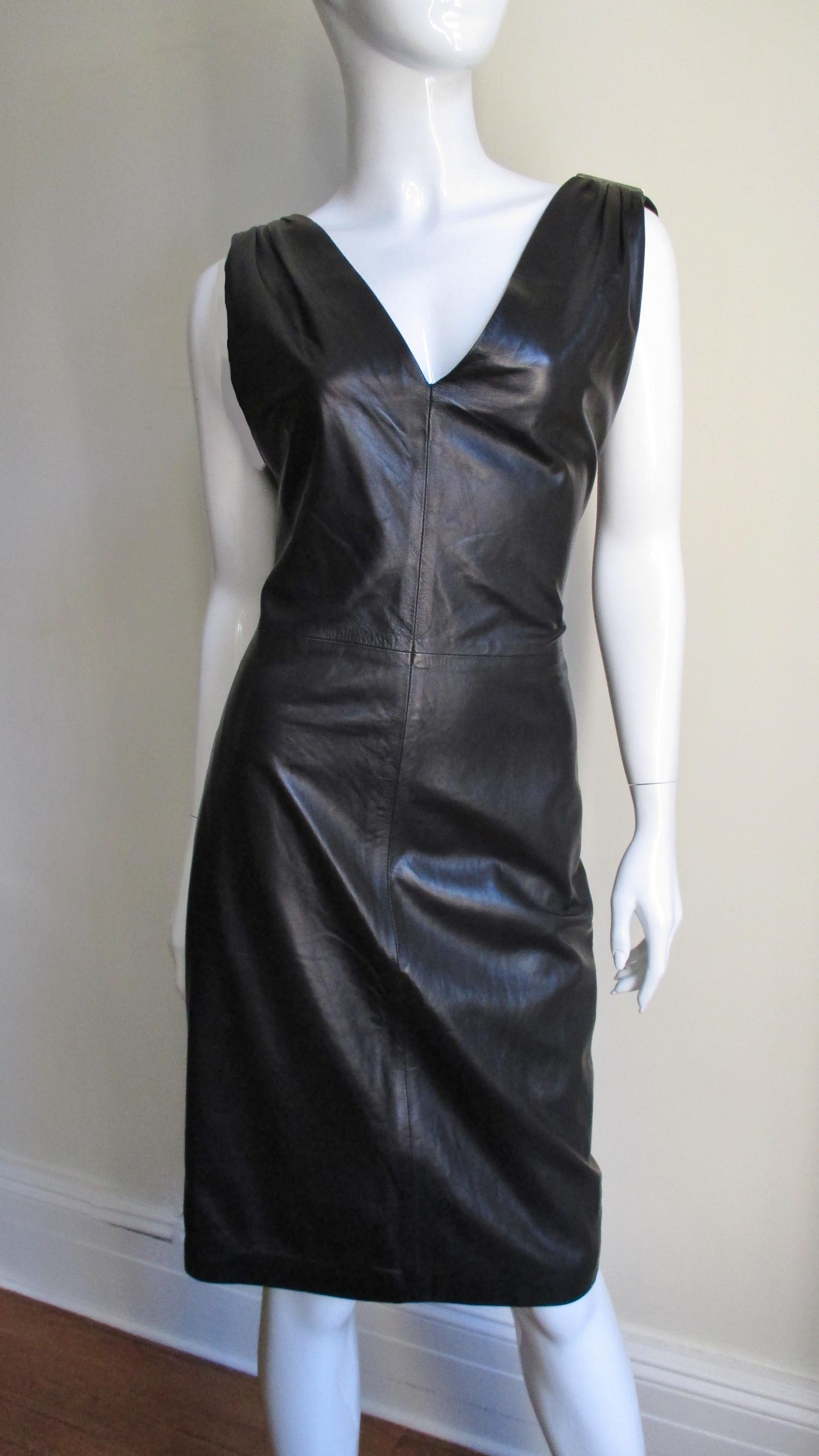 A fabulous black leather dress from Gianni Versace. It is sleeveless with a V neckline front and plunging V to the waist in the back. The shoulders are gathered onto a fine gold metal bar with the trademark Versace Greek Keys insignia along their