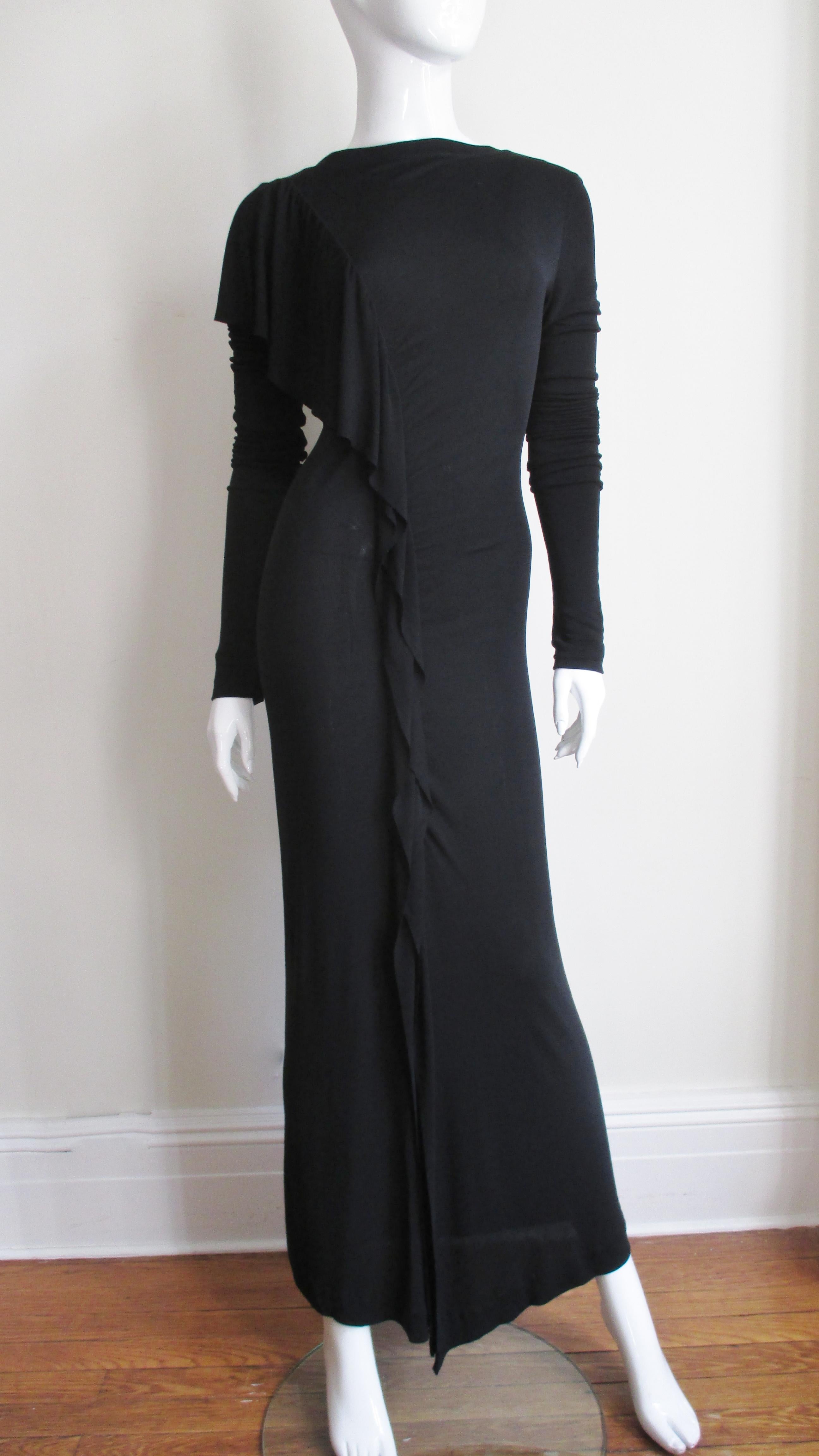 A super black silk jersey dress from Jean Paul Gaultier.  It has a bateau neckline and fitted with a gradated ruffle starting at the front of one shoulder straight down the front to an opening above the knee.  The sleeves are extra long meant for