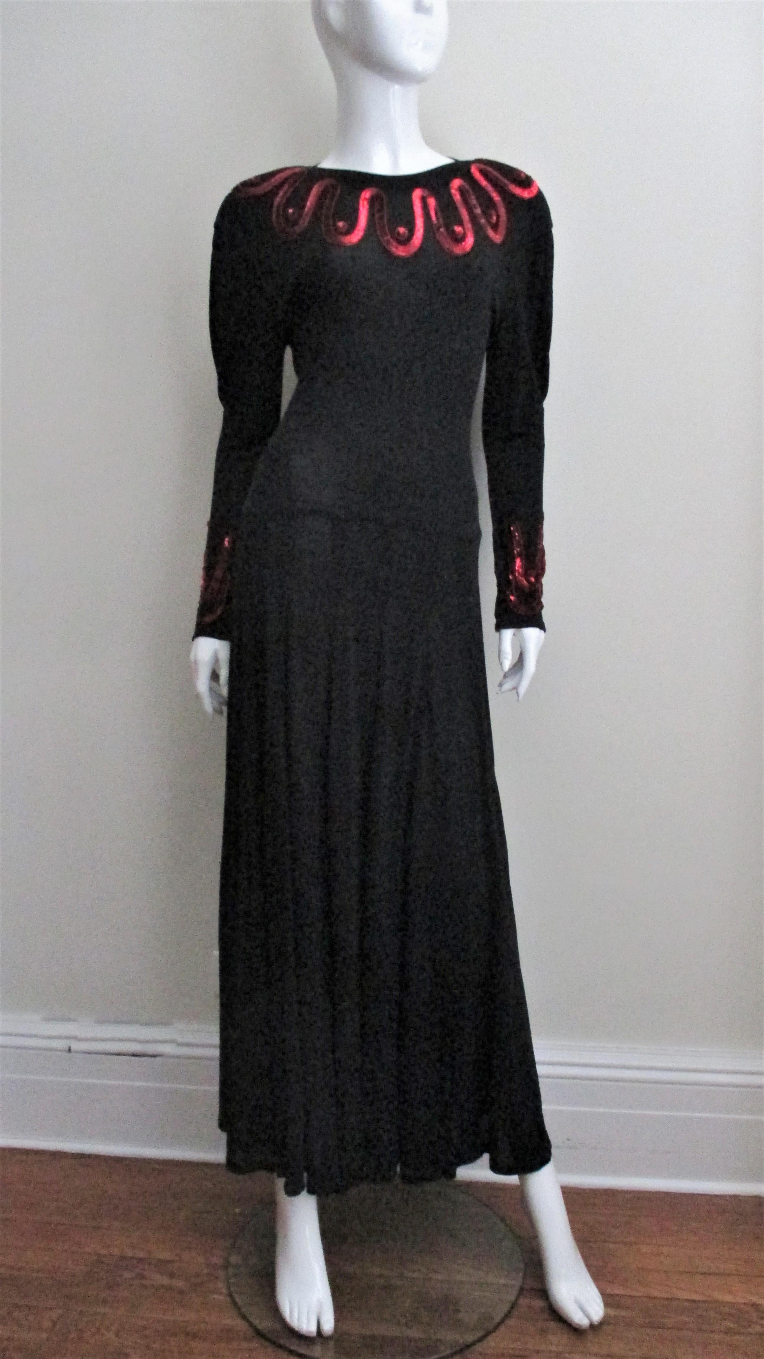 Beautiful rich black silk jersey dress from Jean Muir highlighted with waves of bright red sequins around the neck and cuffs.  It has lightly padded shoulders, slight dolman sleeves with an upper arm inverted pleat giving the upper arm a little