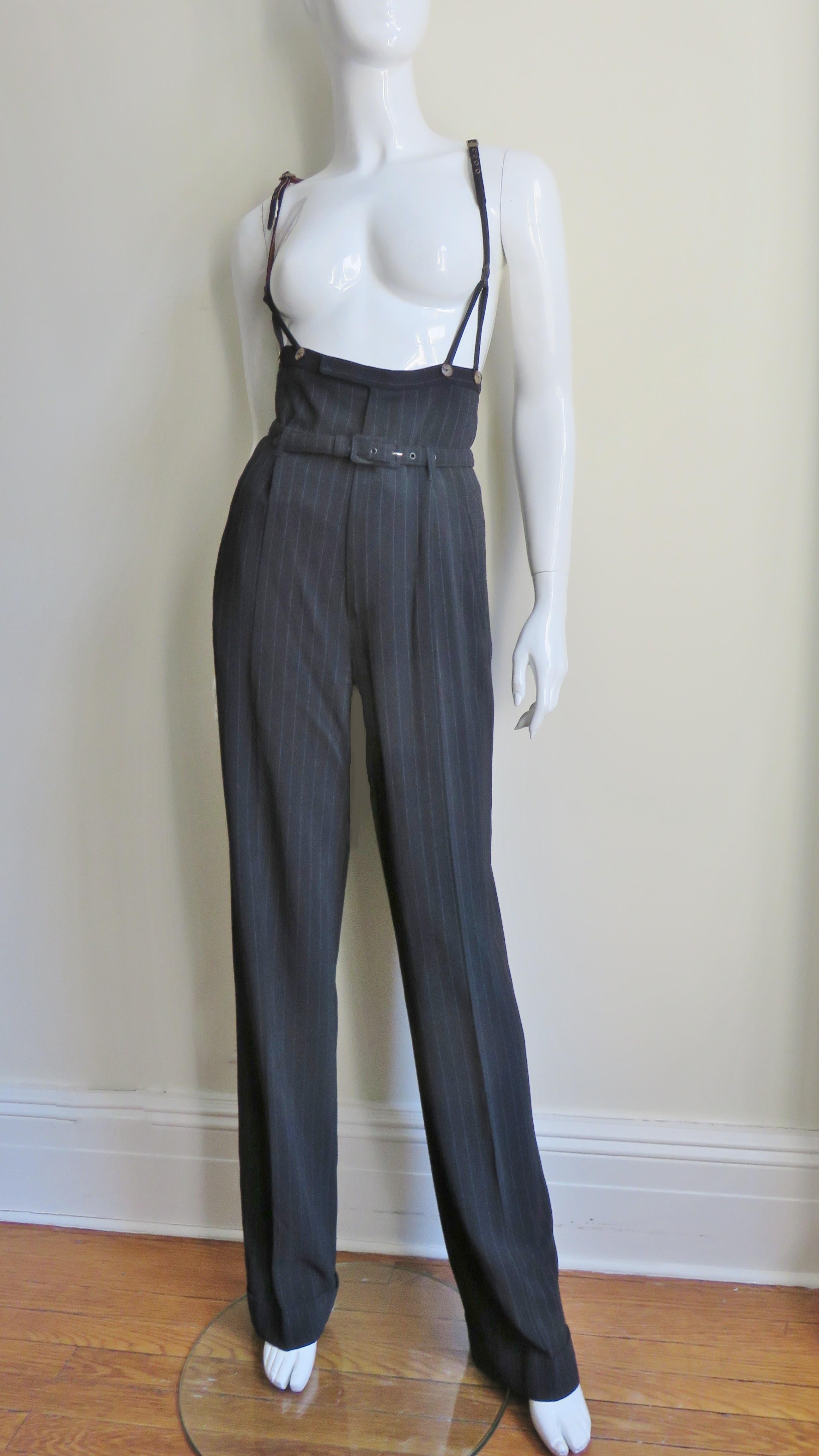 Fabulous black with white pinstripe high waist pants from Jean Paul Gaultier.  High waist with matching adjustable suspenders that button onto the pants and a matching belt at the natural waist where there is pleating and 2 front welt pockets and