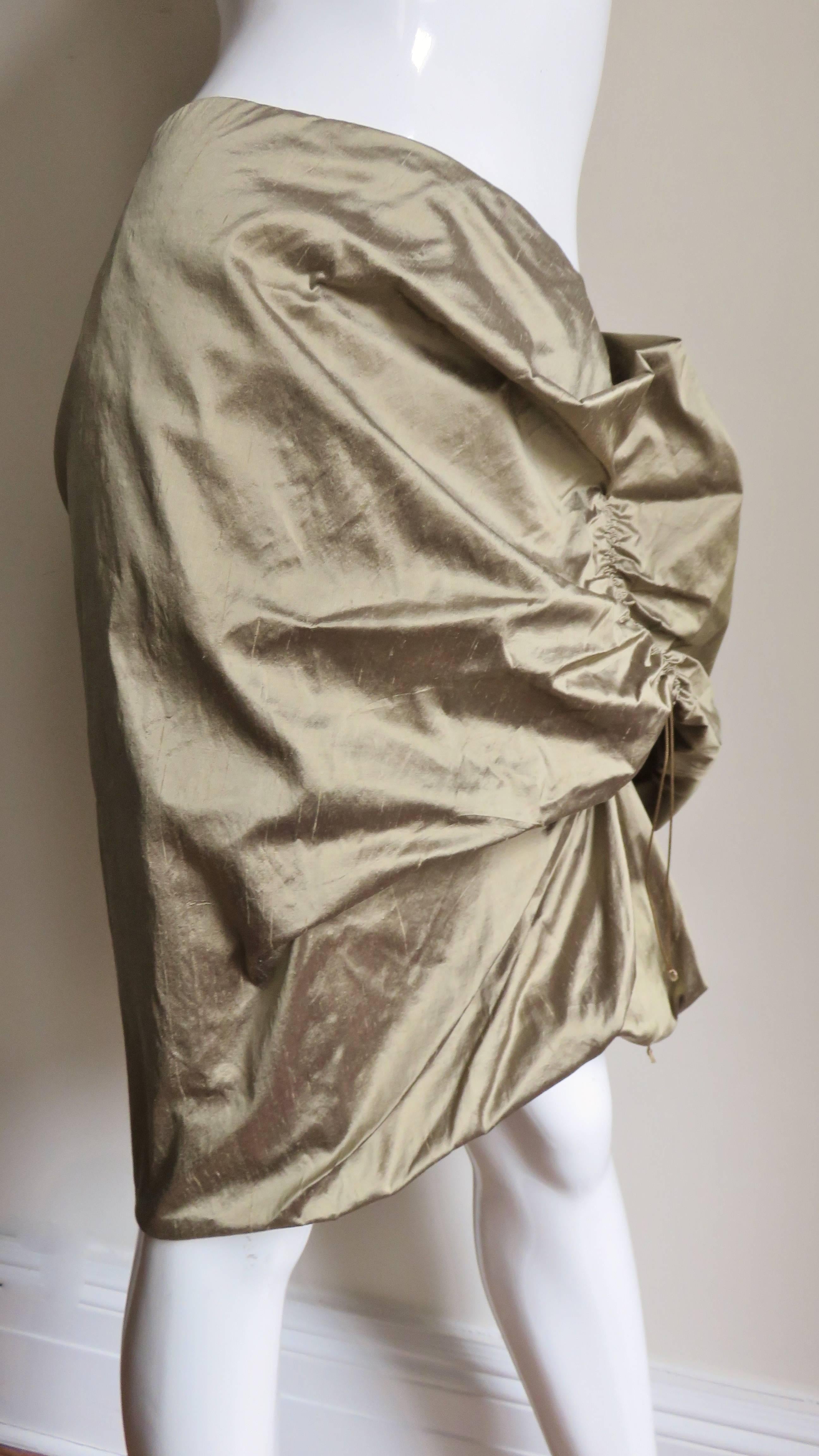 A fabulous gold silk skirt from Christian Lacroix.  It can be shaped in endless machinations by lengthening or shortening the drawstrings.  It is lined in the same fabric and has a side zipper. 
Appears unworn condition.  Fits size Small,