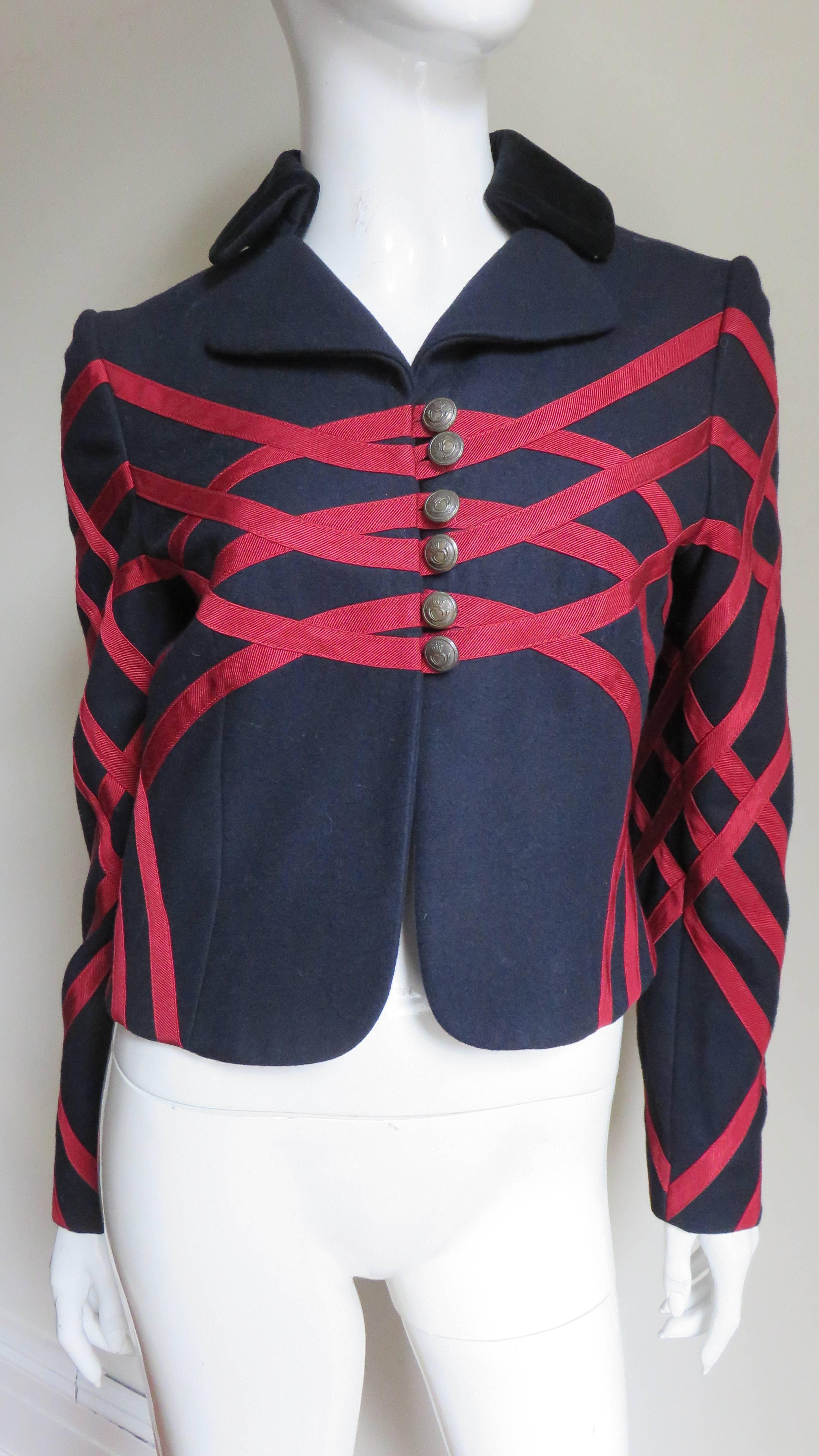 A gorgeous navy wool jacket from Moschino with red grosgrain applique in abstract patterns front, back and along the sleeves.  It has a navy velvet rounded lapel collar plus heart and crown embossed brass buttons and loops closures cleverly placed