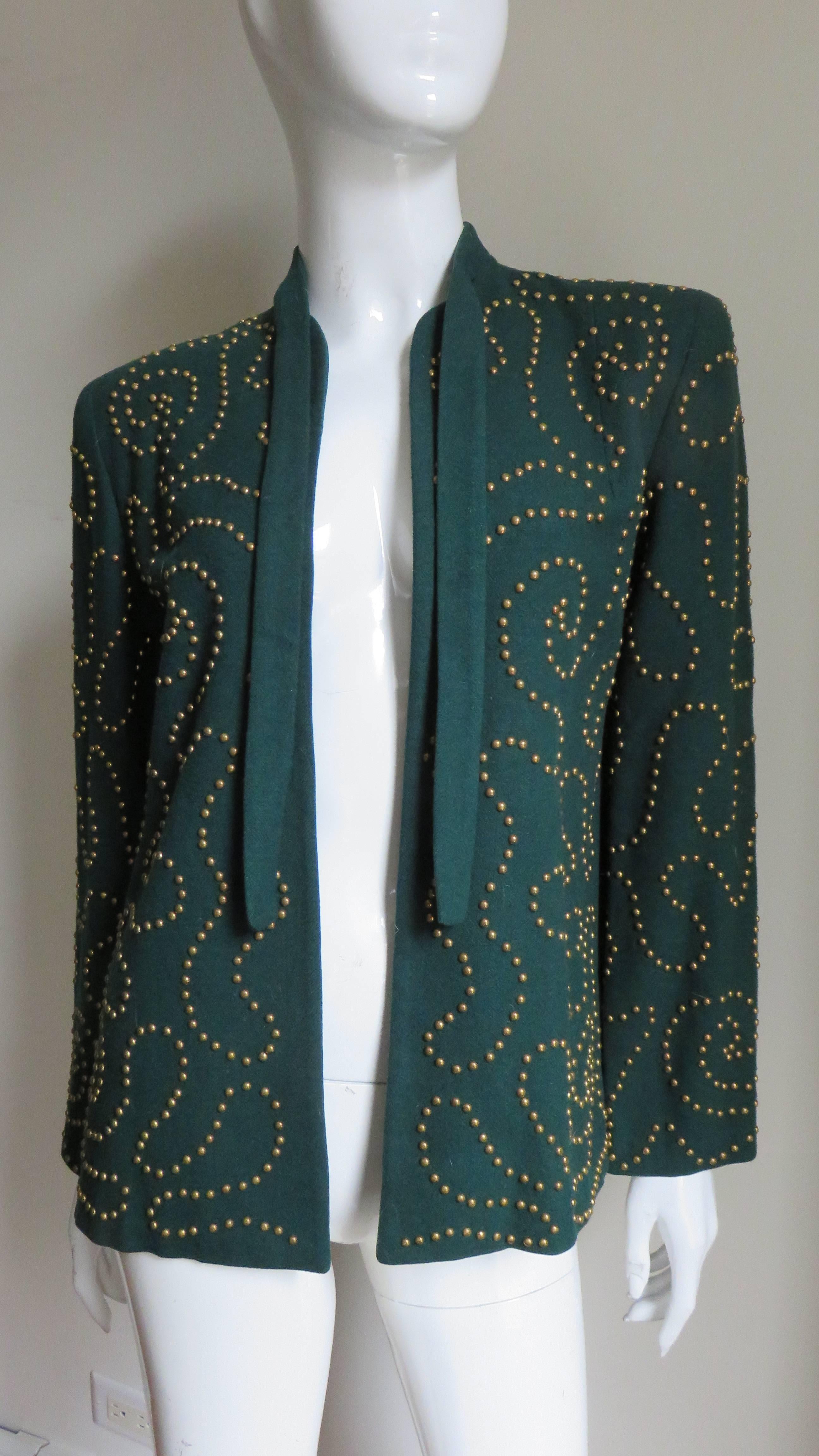 A stunning forest green wool jacket adorned with brass studs in an abstract pattern throughout.  It has a tie at the neckline, shoulder padding and is fully lined in black.  
Fits sizes Small, Medium.

Bust  Open
Shoulders  16