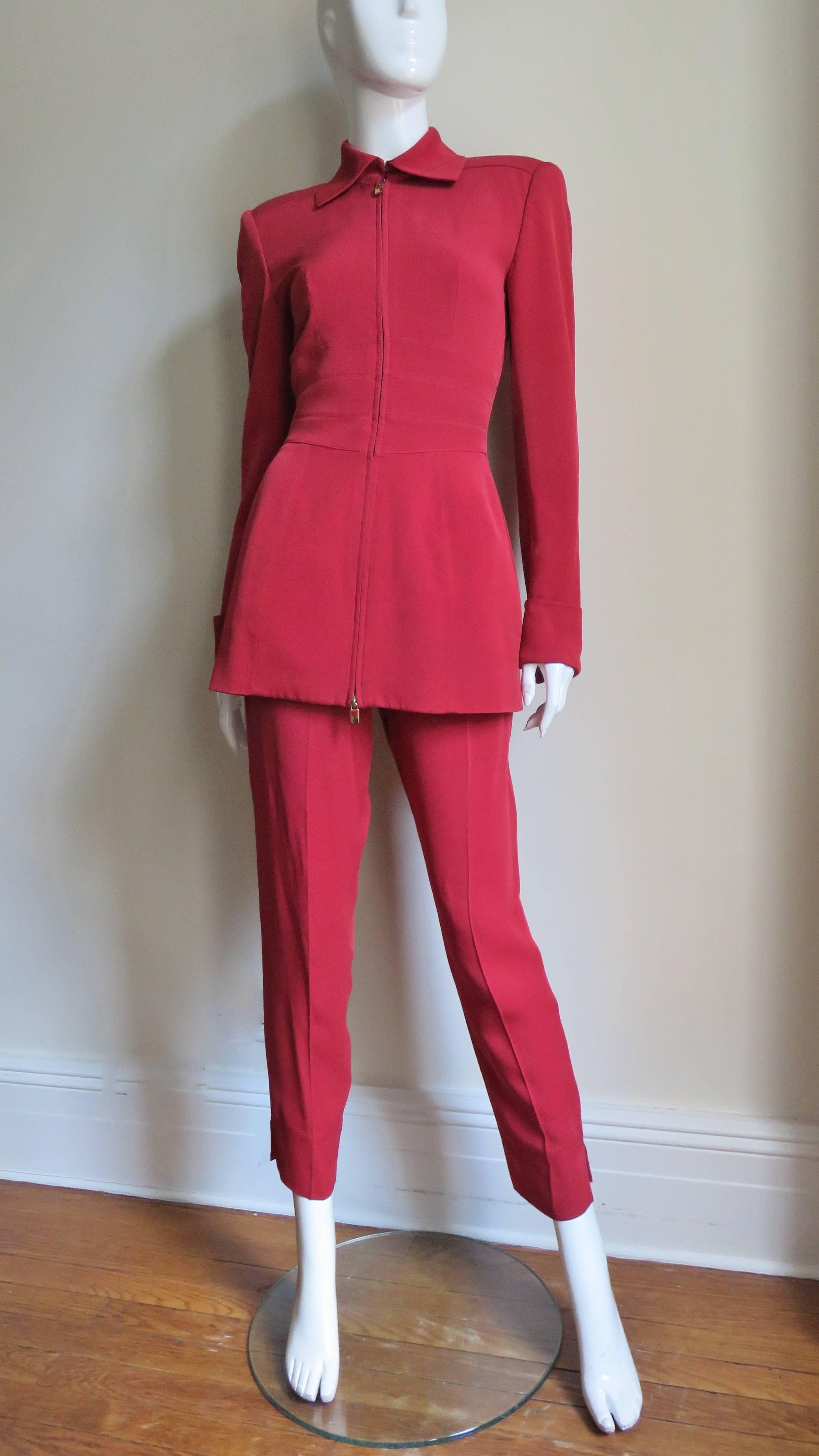 A fabulous red pant suit by  the late, great Claude Montana. The jacket has a pointed collar, shoulder padding, a back yoke, seaming around the waist and long sleeves with zipper cuffs.   It closes up the front with a zipper with matching red metal
