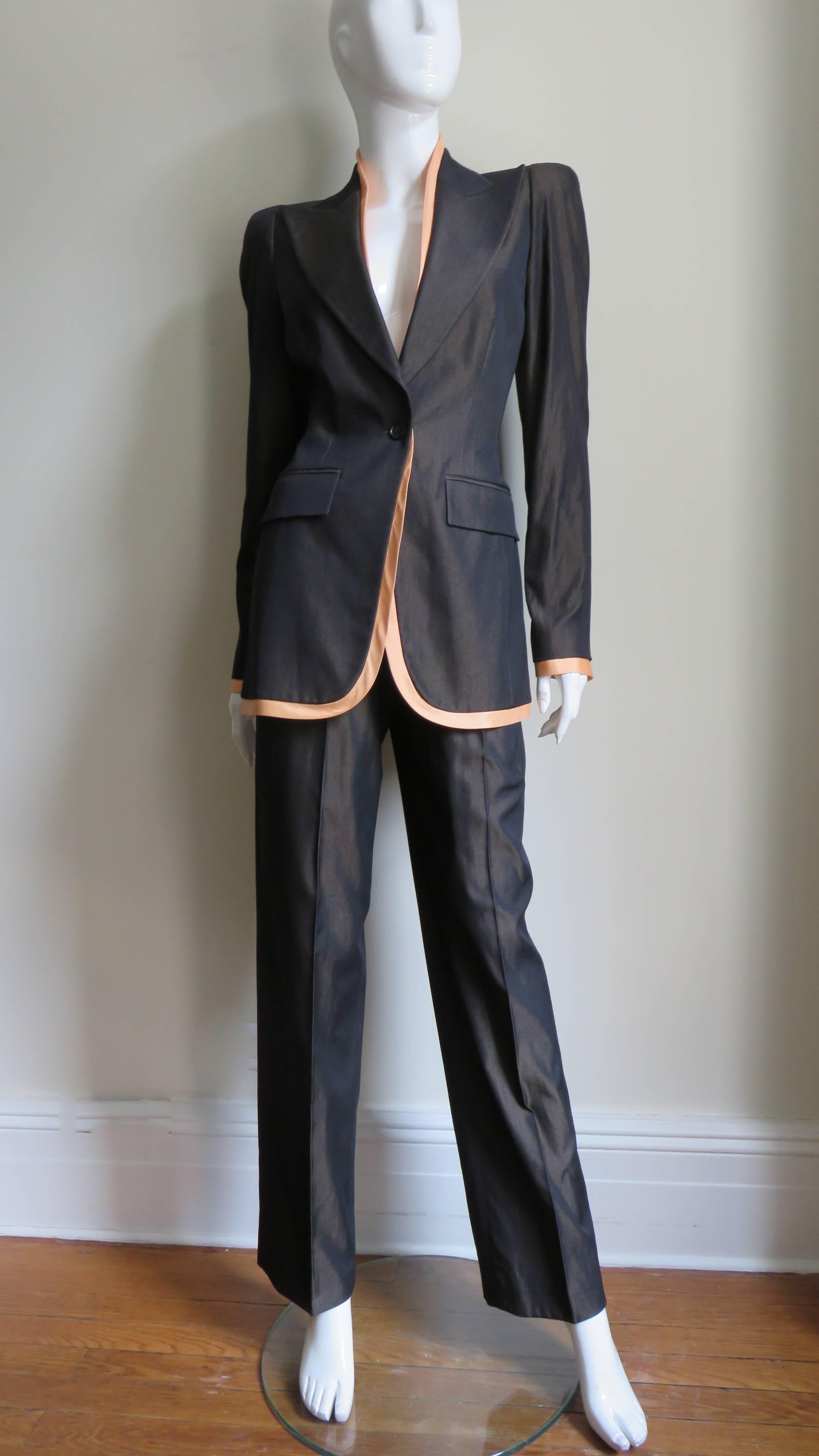 A fabulous brown silk suit from an early Alexander McQueen collection.  The long jacket has shoulder padding, peak lapels, flap pockets, a breast pocket and one button closure.  There is an slim inset of nude silk inside peeking out of the neckline,