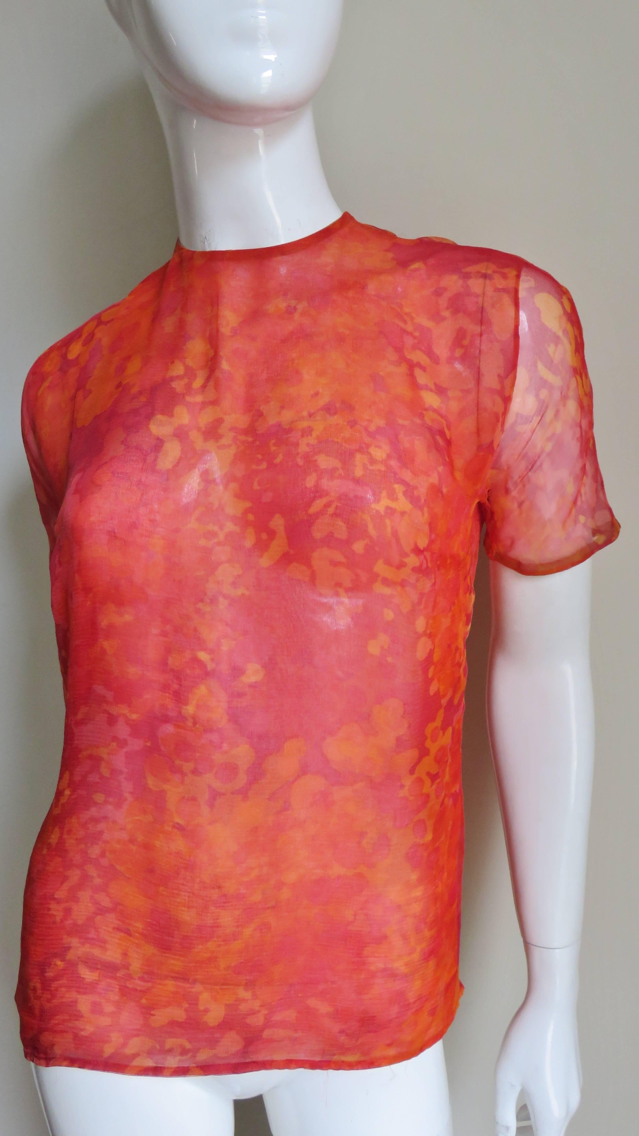 A very pretty silk blouse by Pauline Trigere.  It is made of 2 sheer layers of abstract pattern silk in shades of red and orange.  There are couture details by way of bound buttonholes and self covered buttons up the back.  There is delicate hand