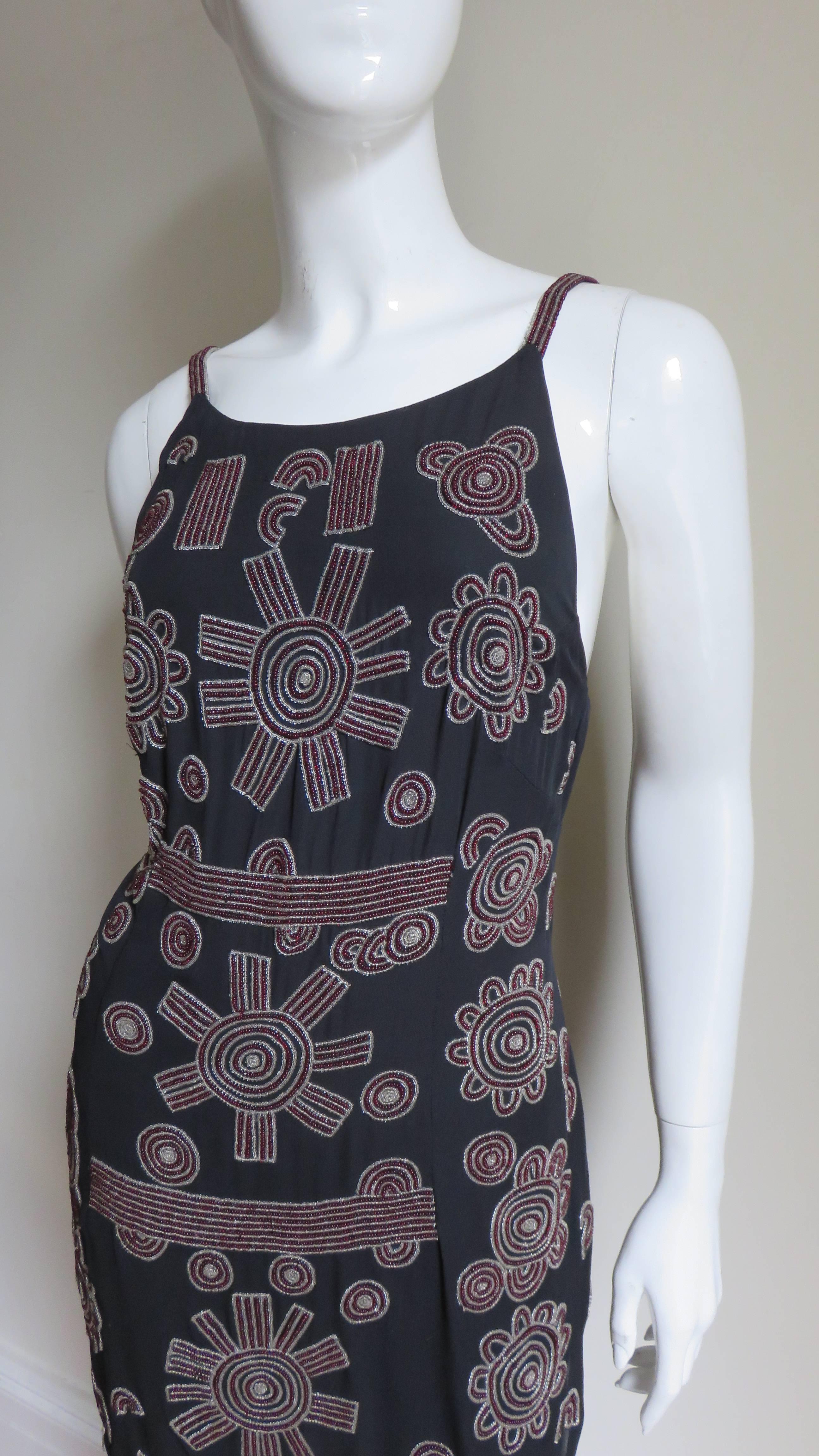 Beautifully beaded in clear and burgundy glass beads forming intricately detailed patterns of circles and lines on navy silk. Low back with zipper, shirttail hem and fully lined in the same navy silk. Absolutely beautiful.
Appears unworn. Fits size