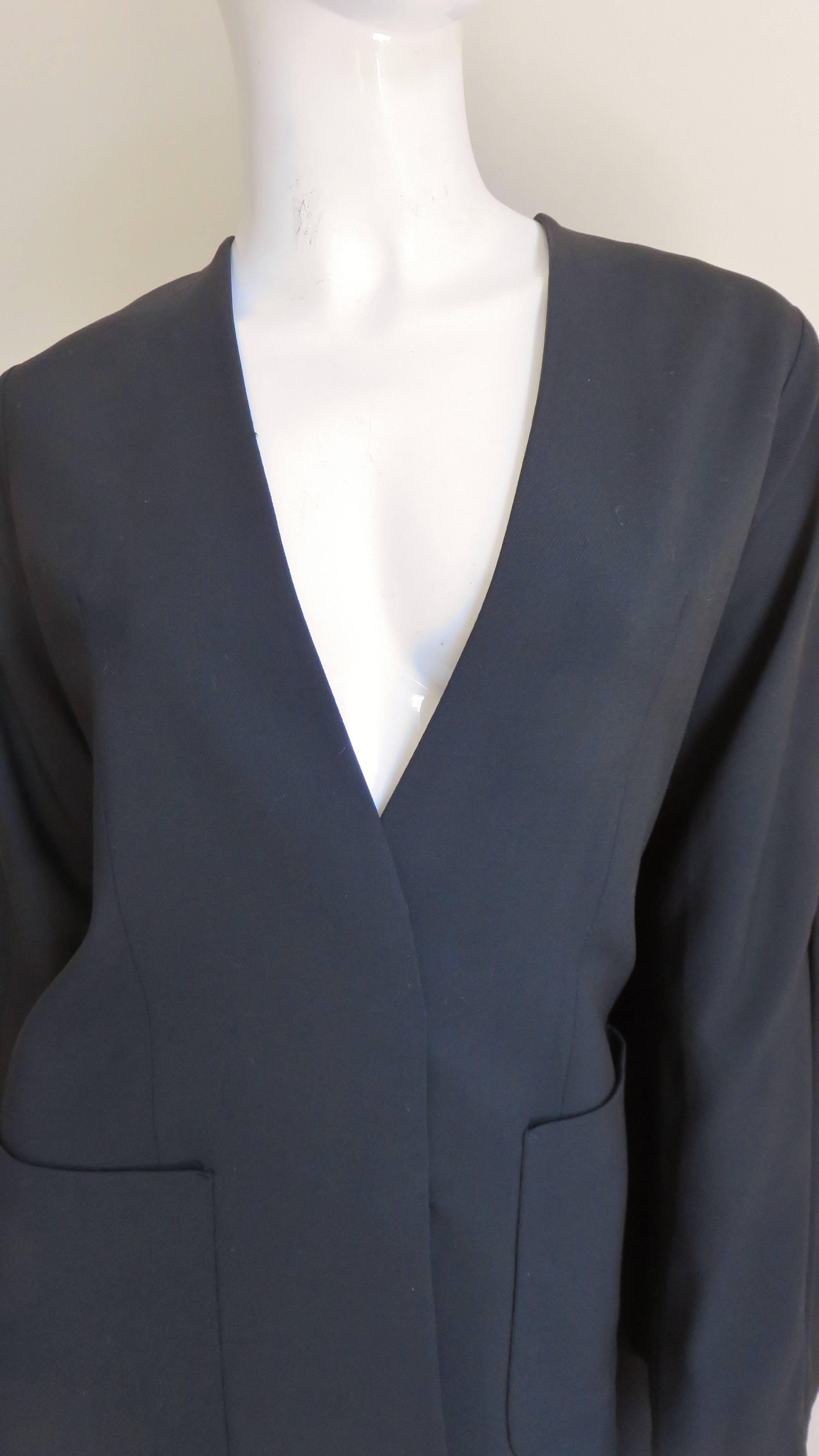 A great dramatic black wool jacket from Martin Margiela.   It is collarless with long sleeves, an invisible button front placket and 2 front patch pockets.  Stunning from the back - from the shoulders and along the back of each sleeve emanates a