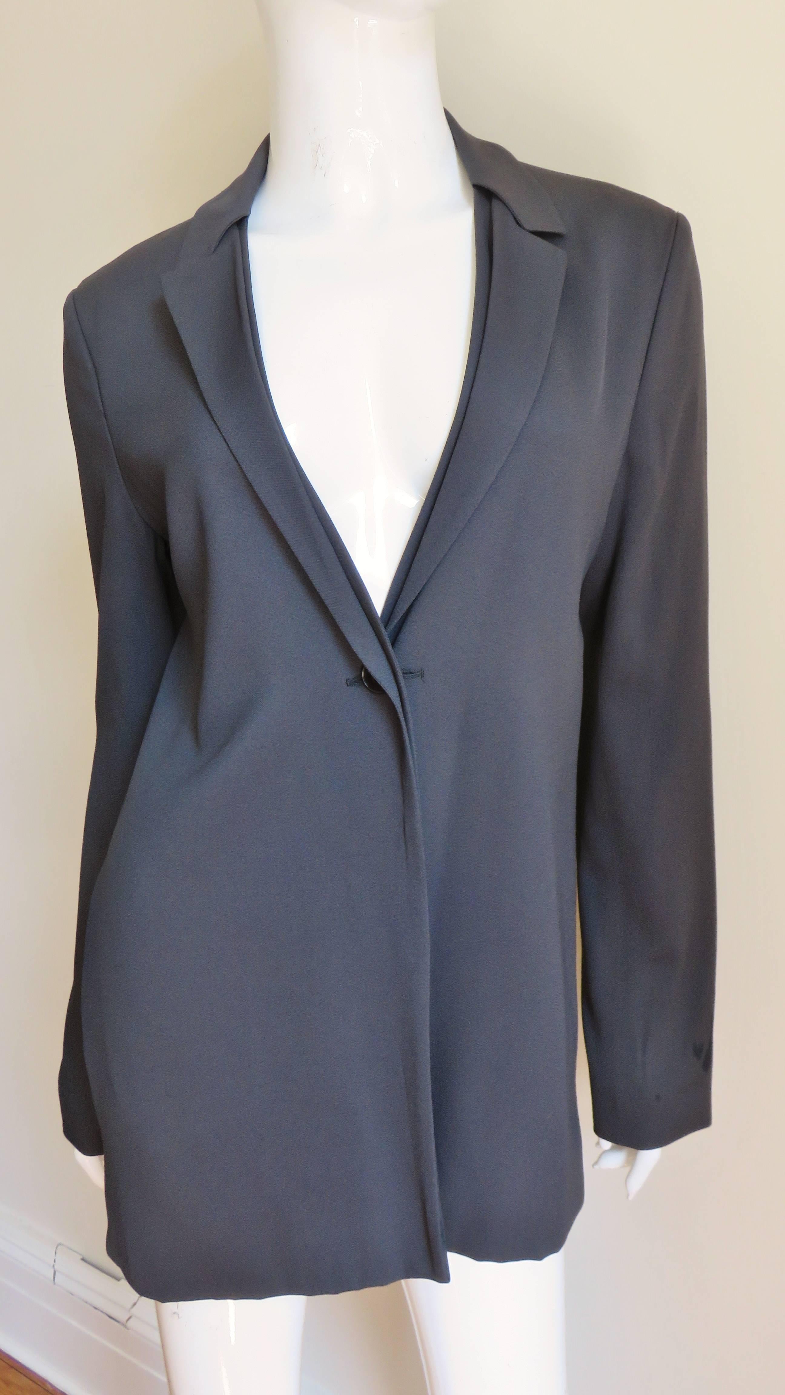 A gorgeous medium weight charcoal silk jacket from German minimalist designer Jil Sander.  It has long sleeves and presents as an ordinary impeccable blazer with hidden buttons but turn it around and it is backless.  Also when the jacket front top