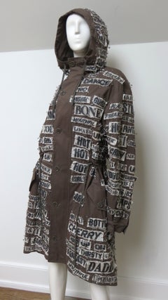 Parka oversize de Moschino Couture en color marrón, con imperdibles y letras, cordón y capucha