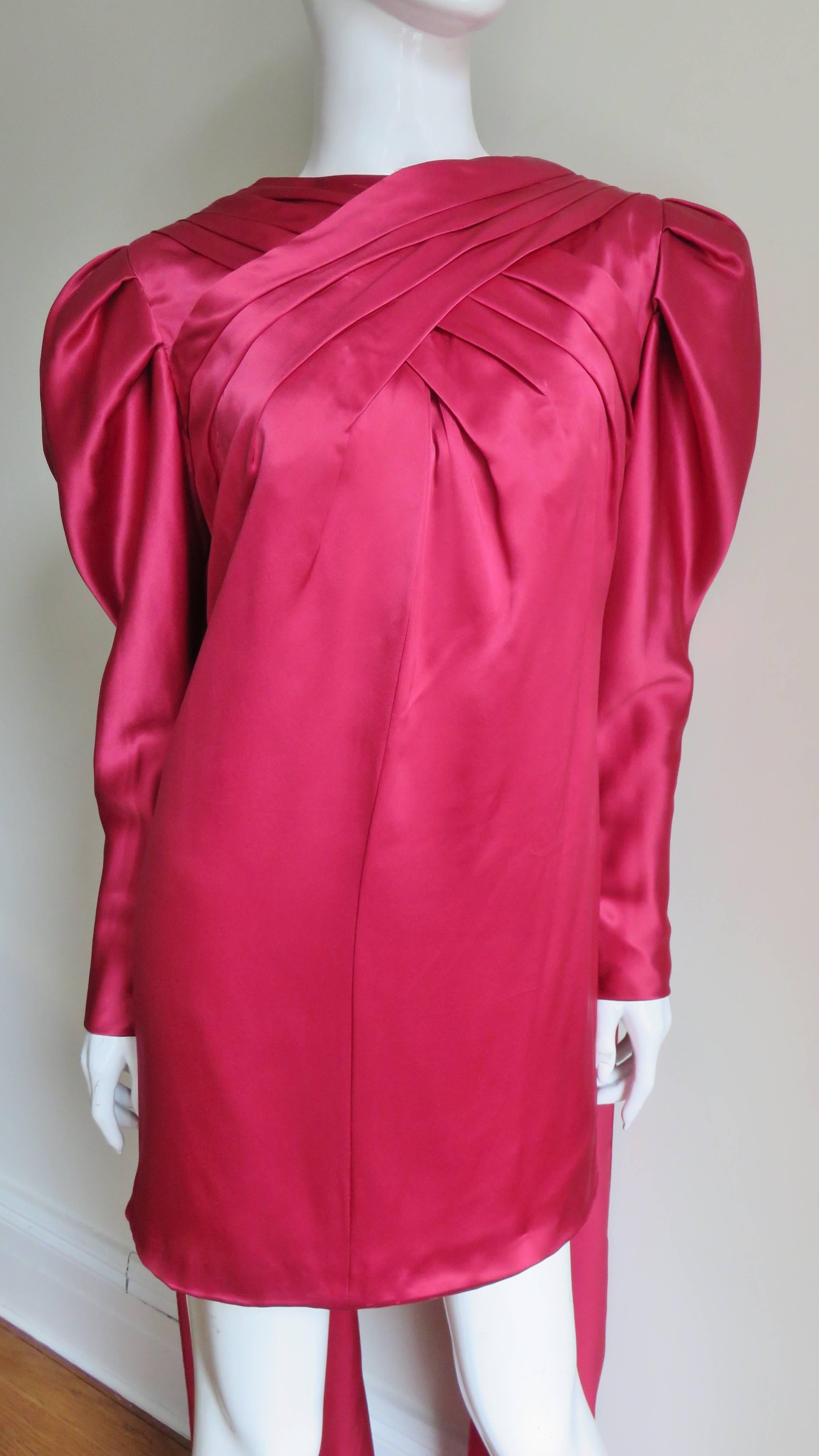 A fabulous deep rose silk dress by Charles Contreri for Wallace Sloves.  It has elaborate pleating crossing at the chest and leg o mutton sleeves with self covered buttons and loops at the wrists.  There is a system of folded silk inside the