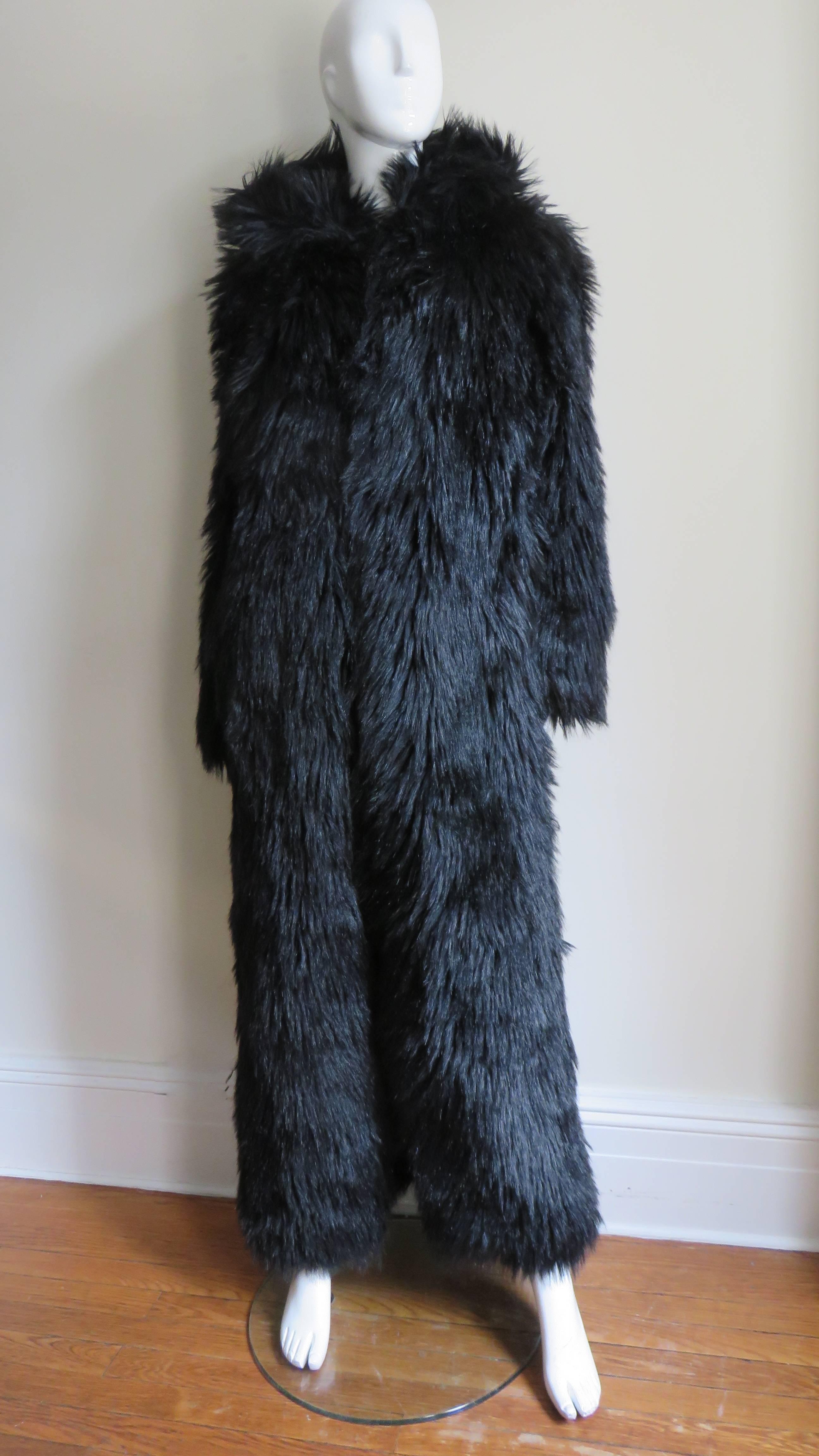 A fabulous black faux fur full length maxi coat by Betsey Johnson.  It has a hood, side seam pockets and long soft luxurious faux fur.  It closes in the front with fur hooks and is lined in black. 
Unworn.  Fits Small, Medium.

Bust  42