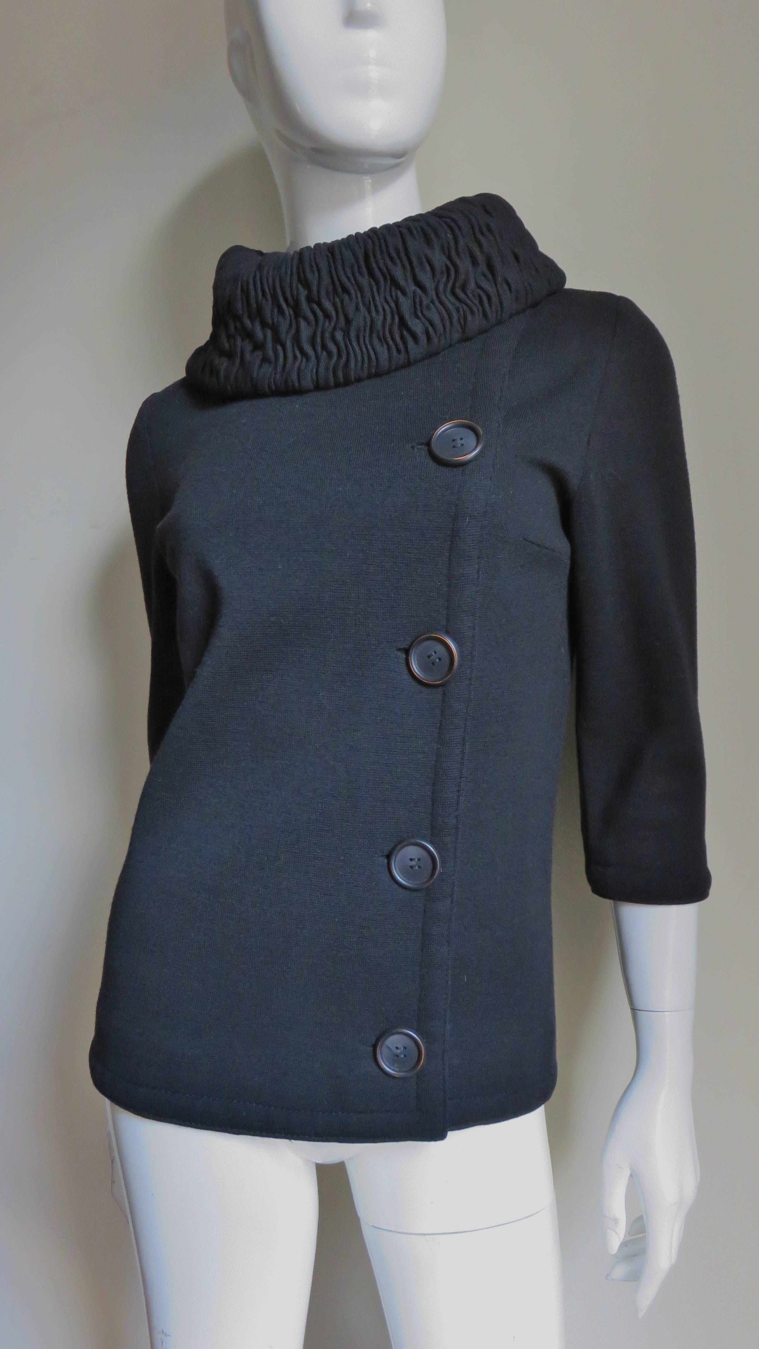 A great black wool knit jacket by Gino Paoli.  It buttons asymmetrically off center front closing with large round black buttons and has 3/4 length sleeves.  The collar folds over and is comprised of detailed rows of ruching closing at the side neck
