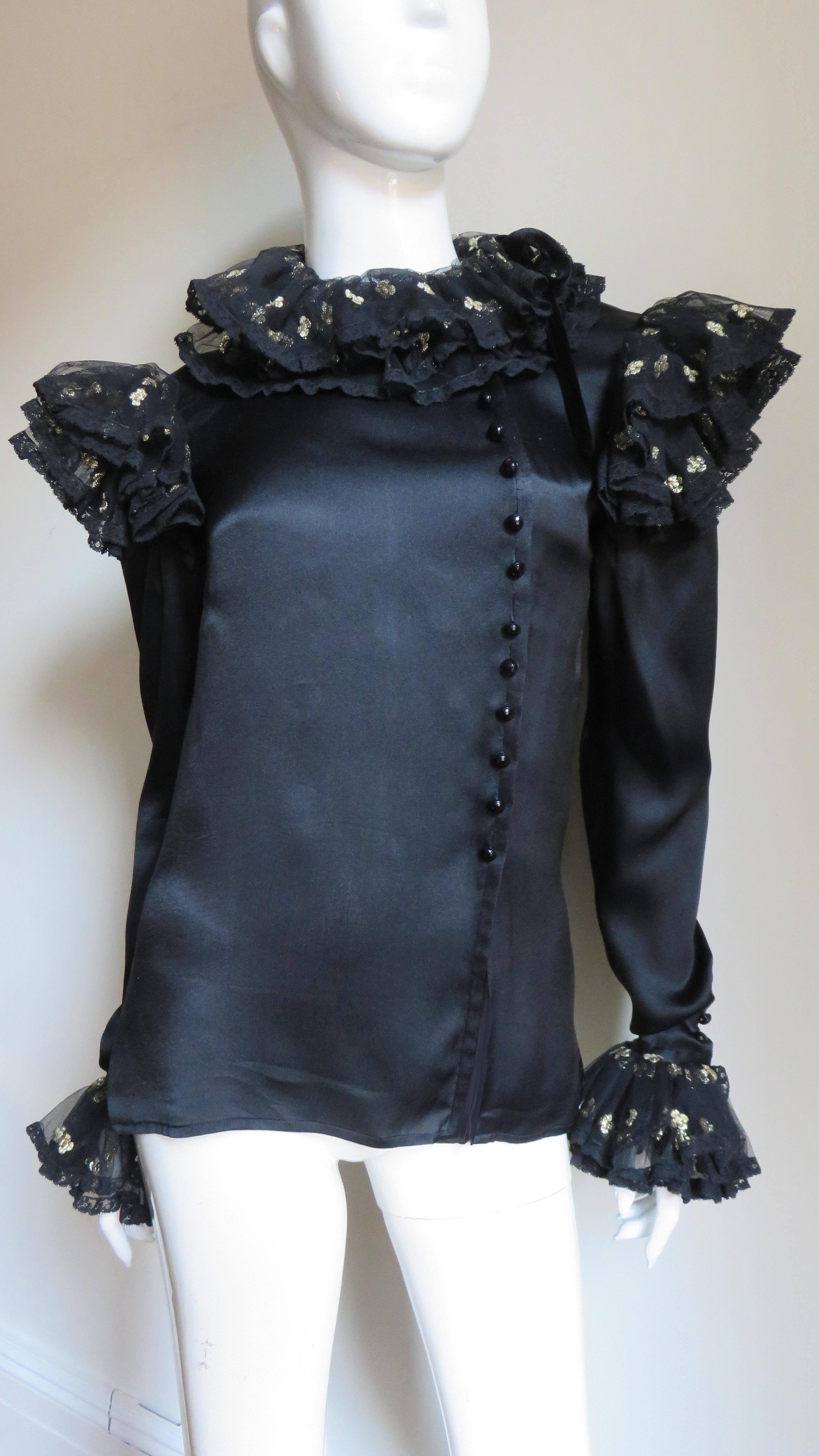A gorgeous black silk charmeuse blouse shirt by Valentino.  It buttons on the side front with delicate black faceted glass buttons and is adorned with layers of beautiful gold flower dotted black lace at the neck, shoulders and cuffs of the long
