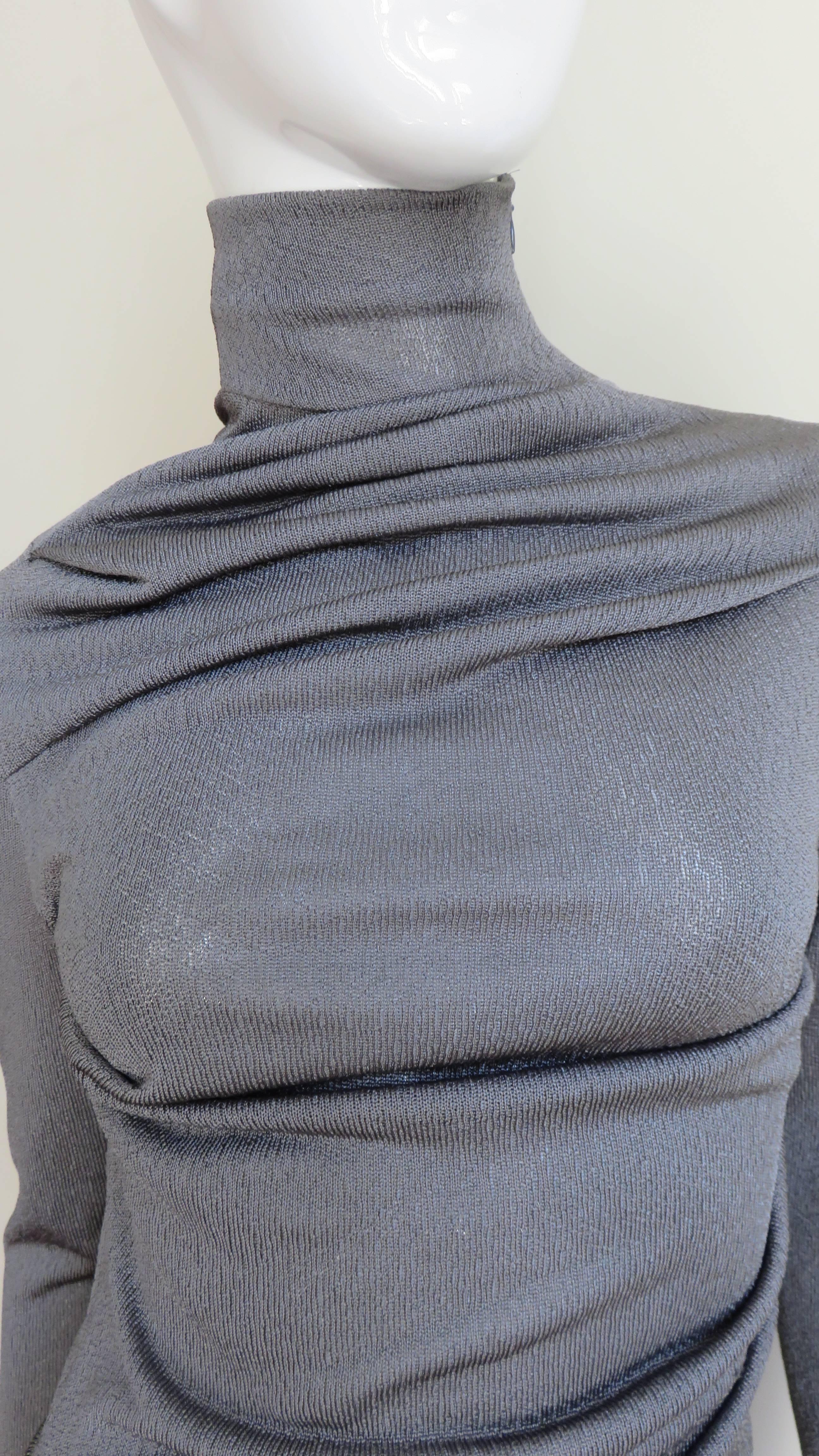 A fabulous draped top in a silvery grey silk knit by Alexander McQueen.  It has a stand up collar and long sleeves. The body drapes diagonally across the front and back creating beautiful lines.  It is unlined and has a shoulder/neck zipper on one