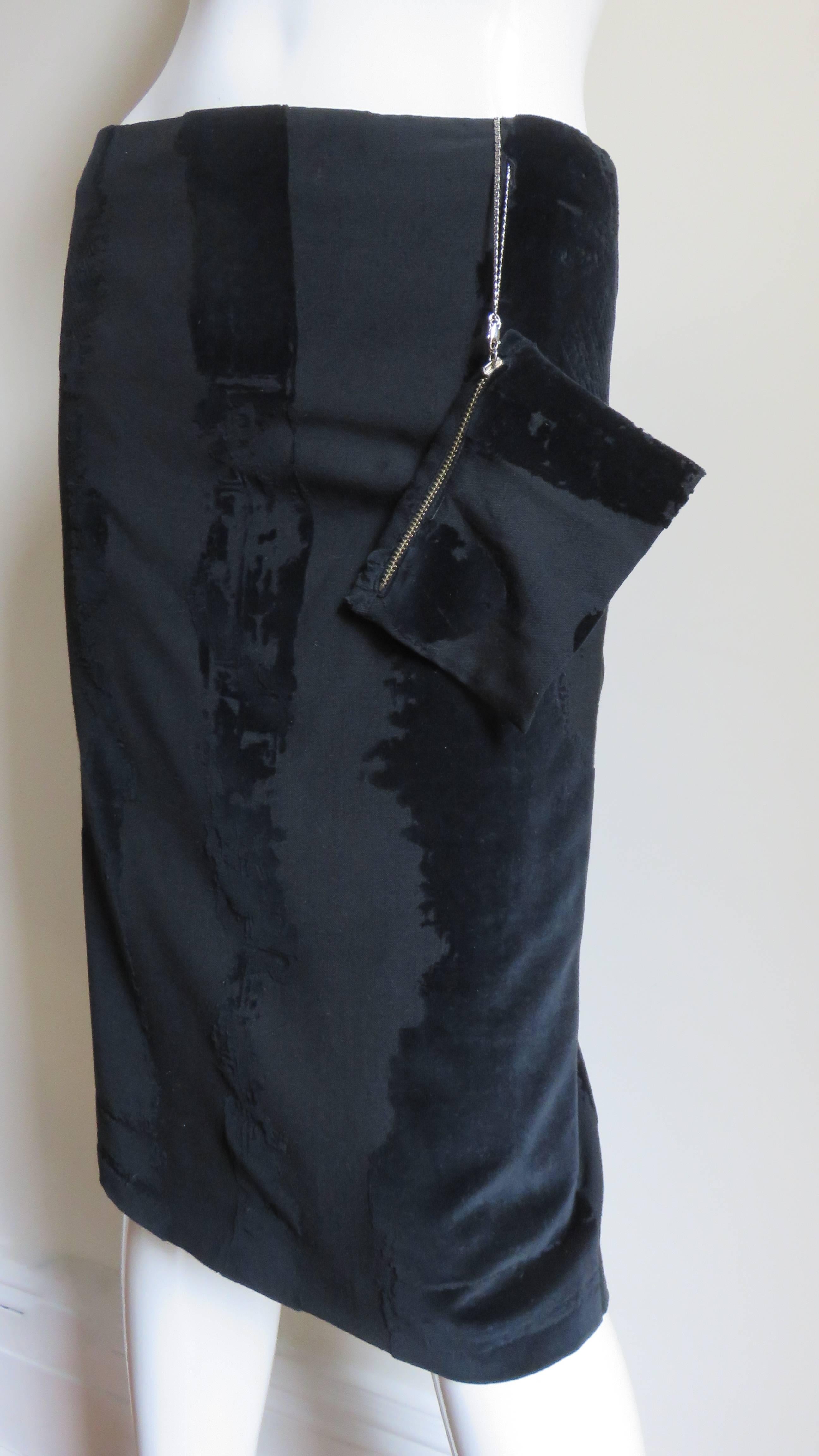 A fabulous black burn out velvet skirt by Jean Paul Gaultier.   It is pencil style with wide abstract vertical velvet stripes and a small zipper pouch attached by a chain at the waist.  It is fully lined, has a center back zipper and a back kick