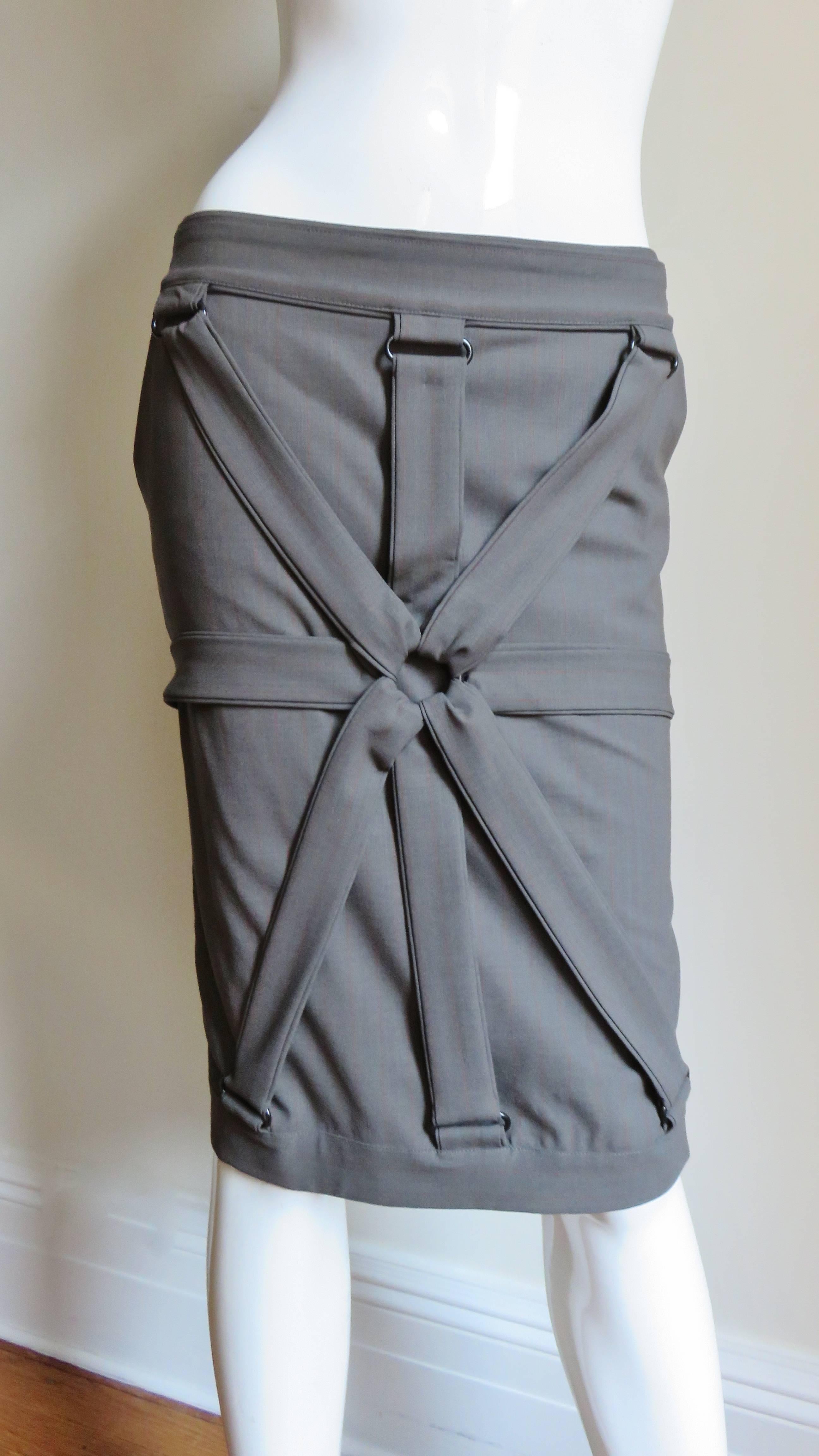 A gorgeous wool jersey skirt from Jean Paul Gaultier in khaki grey with fine subtle rust stripes. It is mid rise pencil style with a waist band, and radiating straps front and back meeting in a center ring.  It has side seam pockets and is fully