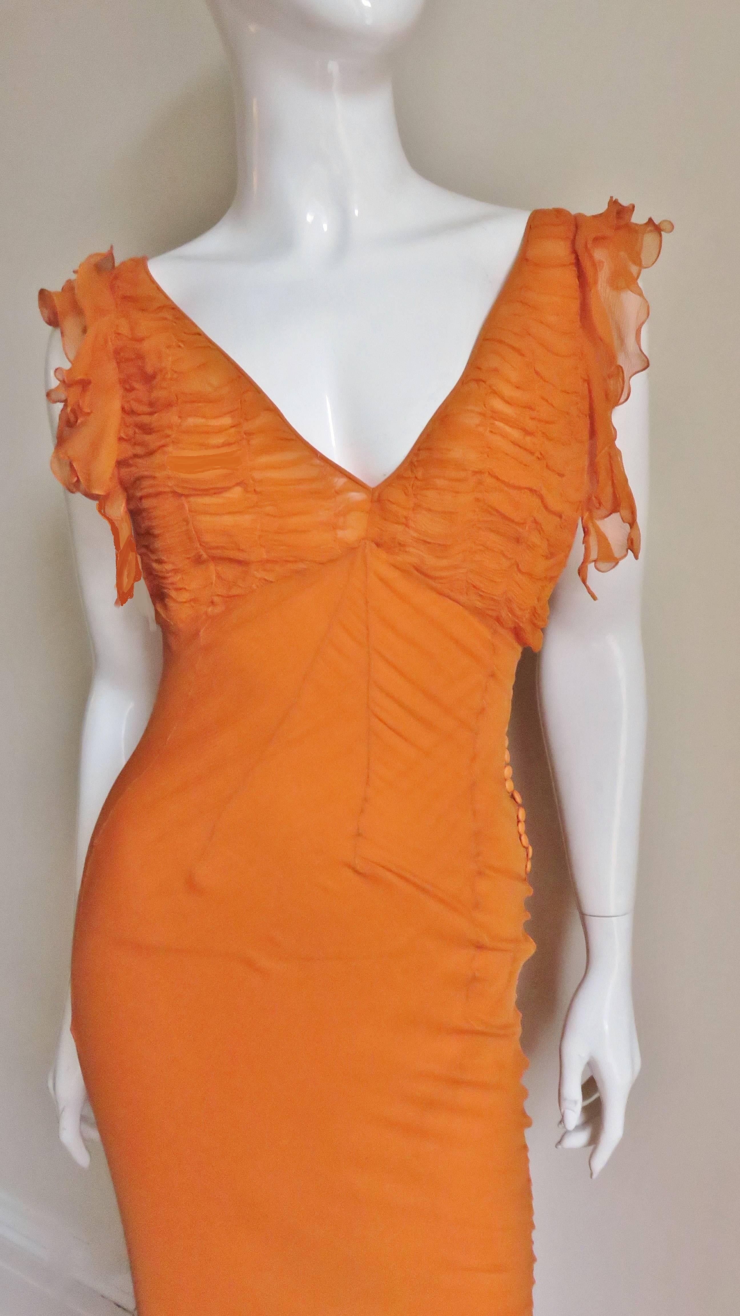 An absolutely stunning orange silk gown by John Galliano for Christian Dior.  It has a plunging neckline front and back plus deep armholes with ruffle edges.   The bust portion of the dress has horizontal ruching. The body of the dress is fitted