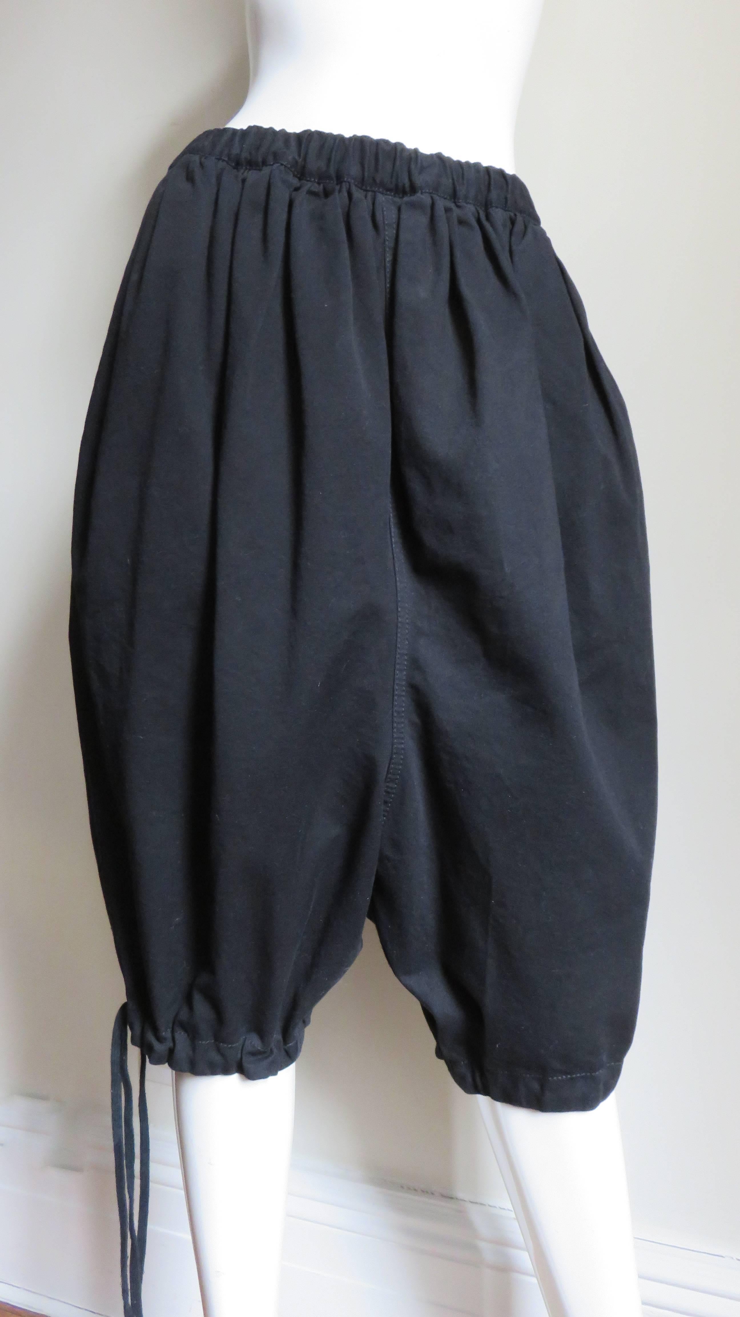 A fabulous pair of dropped crotch pants in rich black denim weight cotton.  They have stretch at the waistband with an inner drawstring from which gathers a full pair of harem style short pants.  There are also functional drawstrings at the legs and