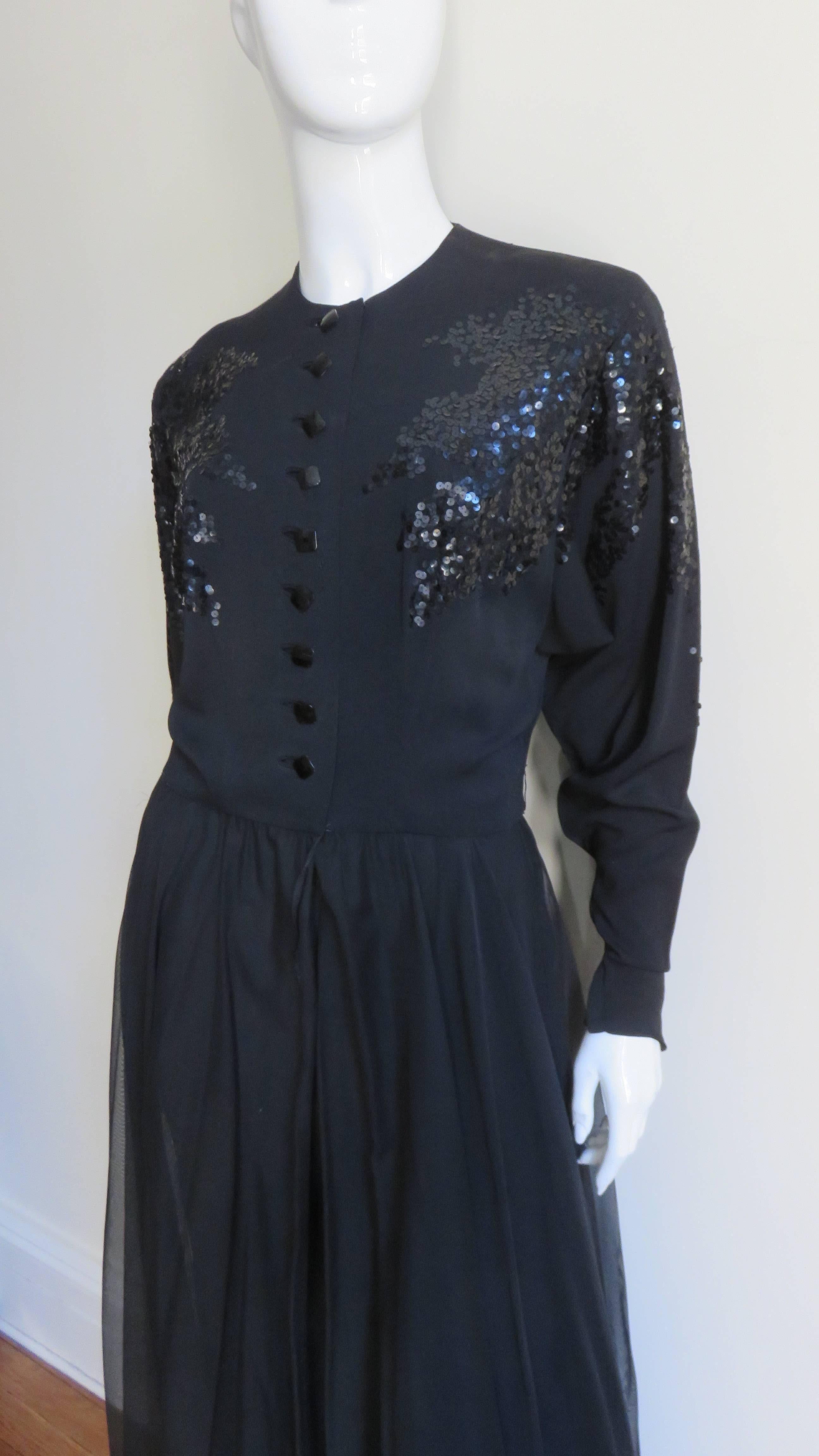 A fabulous hostess set from the 1950s consisting of black pants and an overdress.  The overdress has dolman sleeves with metal zipper cuffs, an elaborate abstract black sequin pattern along the upper front, back and sleeves and black square faceted