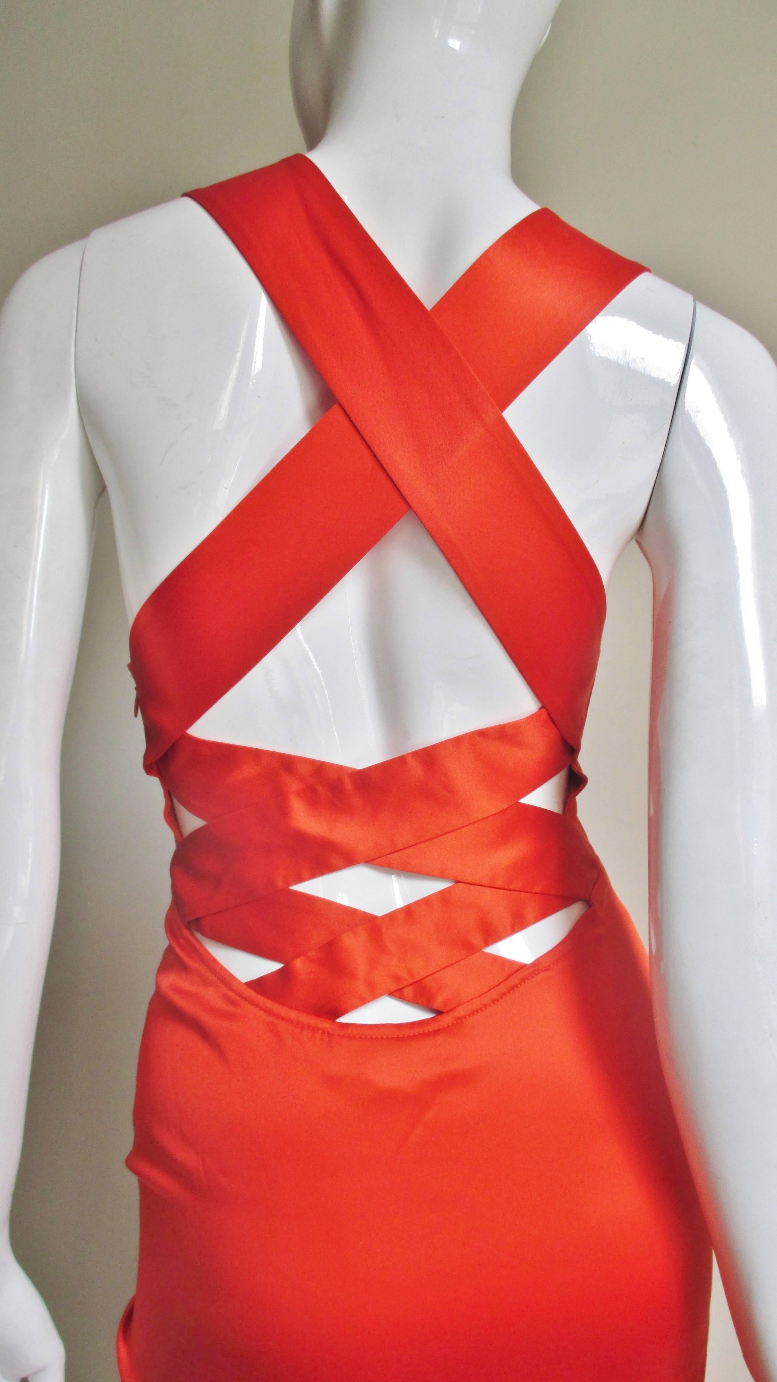 An orange fine silk dress from Versace.  It has a plunging gathered front which is attached to a fitted bodice.  The fitted skirt portion is pieced in angles front and back.  The back is absolutely stunning, low cut with straps crossing at the upper