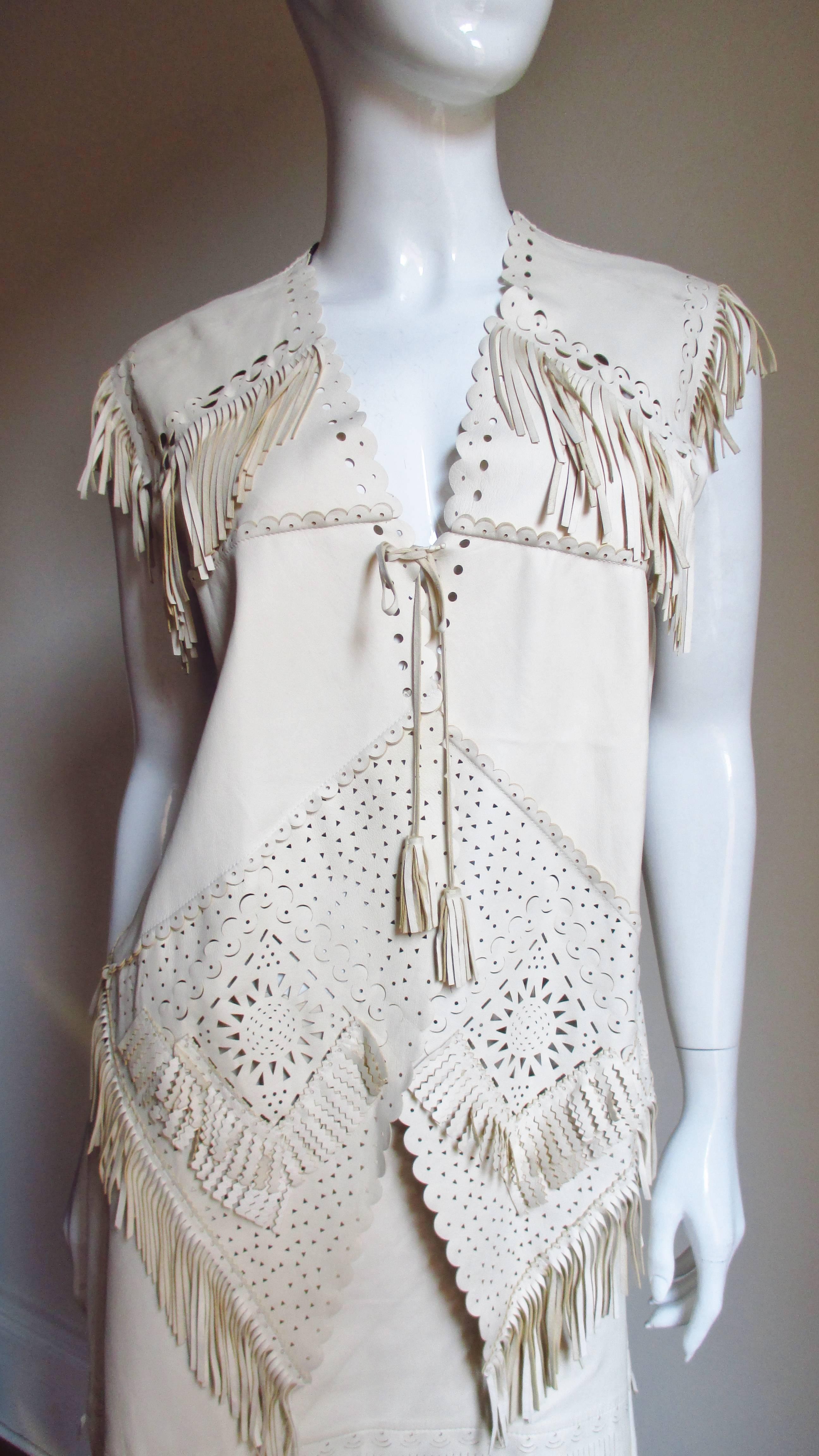 A fabulous set from Jean Paul Gaultier in a very fine, soft, supple bone colored leather.  It consist of a vest/top/jacket laser cut in different shapes and patterns, appliqued with varying lengths of fringe and a pointed front hem.  It has a