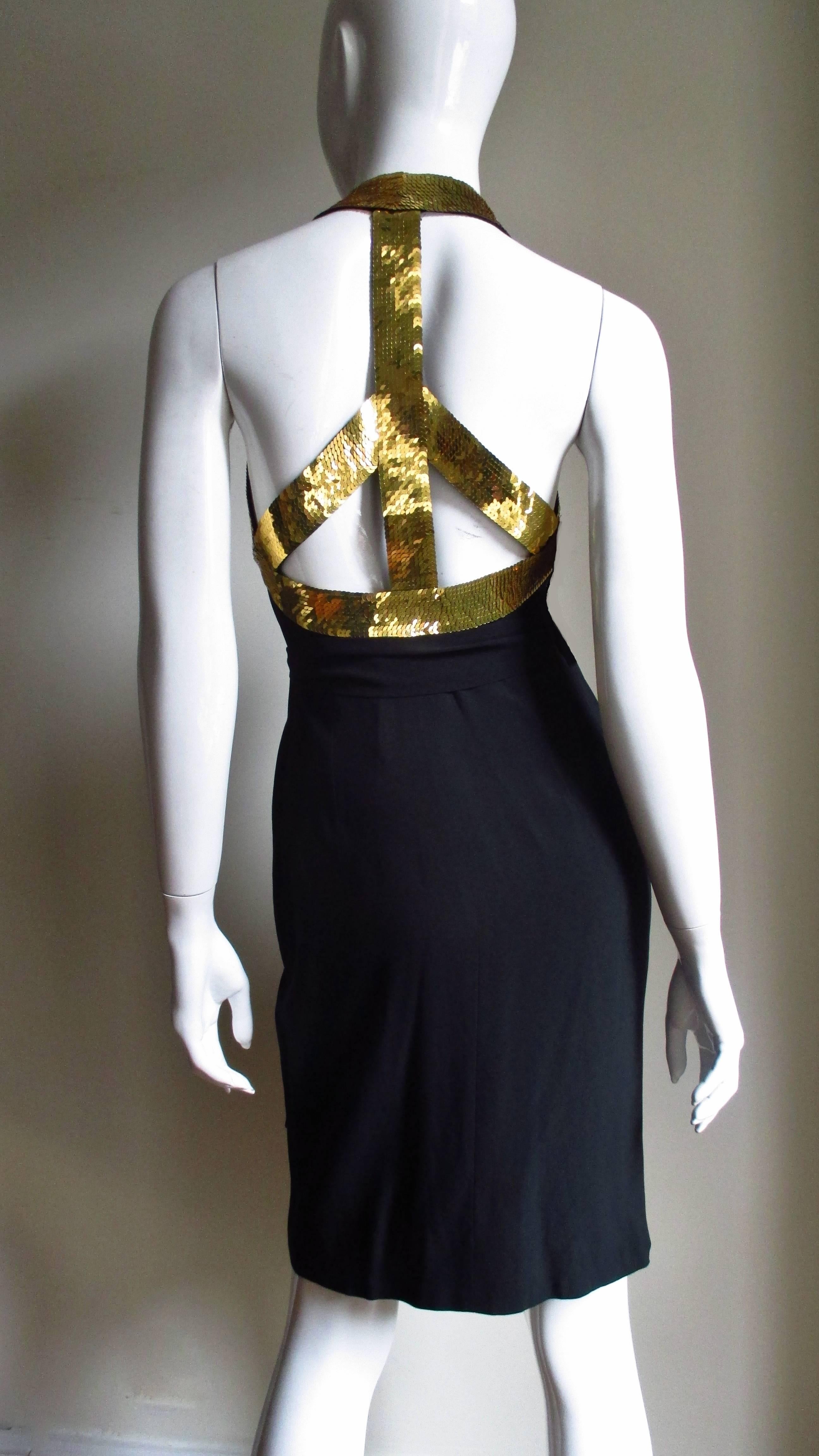 A fabulous black silk halter dress from Moschino Couture. It is a wrap style dress which ties at the waist and has a band of gold sequins around the neck through to the back forming a peace sign.   It is fully lined.  
Fits sizes Extra Small, Small.