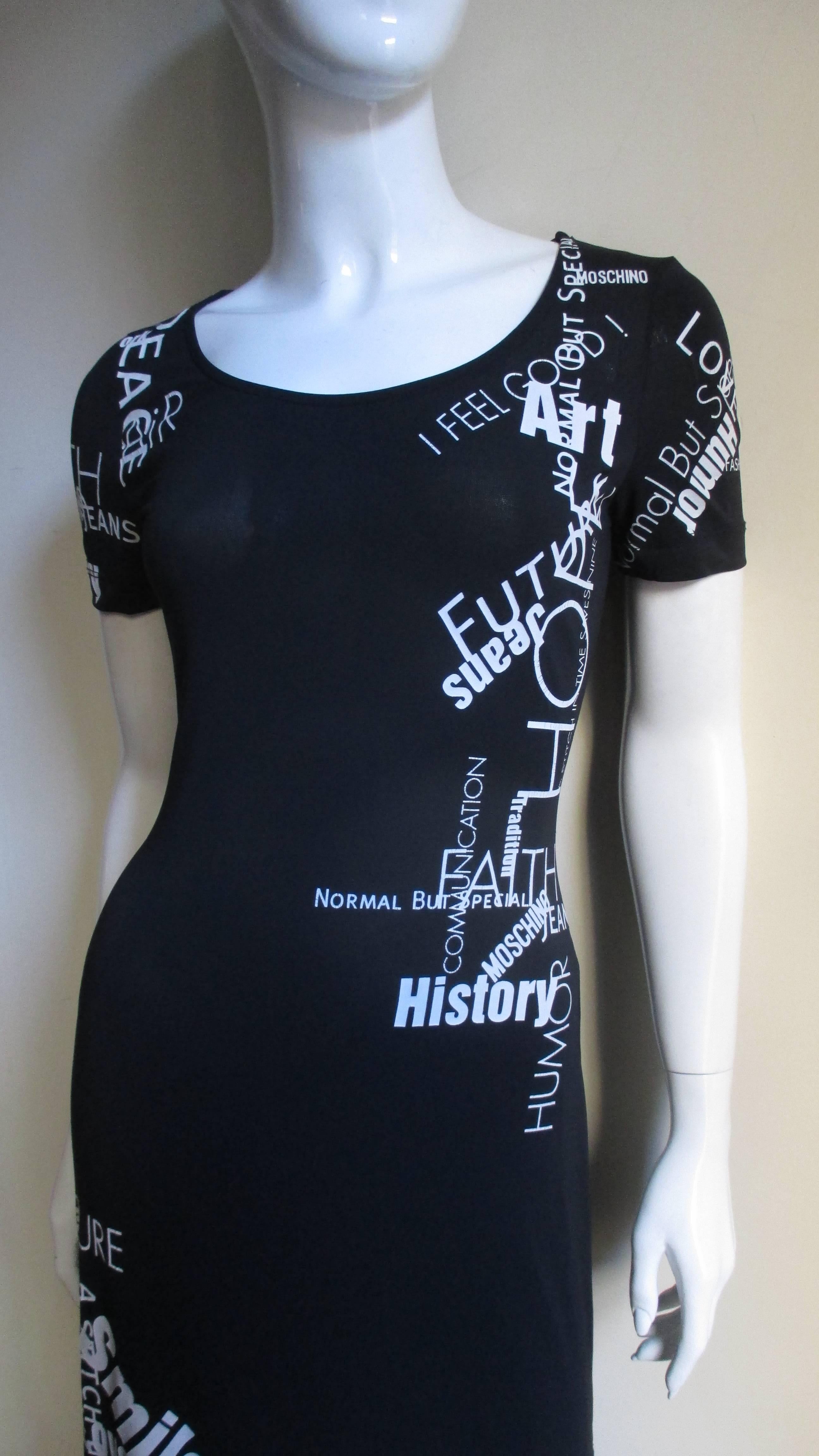 A great t-shirt style dress in black from Moschino.  Is is short sleeved, fitted with a scoop neckline and is covered in a variety of screen printed words and phrases in different sizes and angles including- History, Communication, Future, Hope,