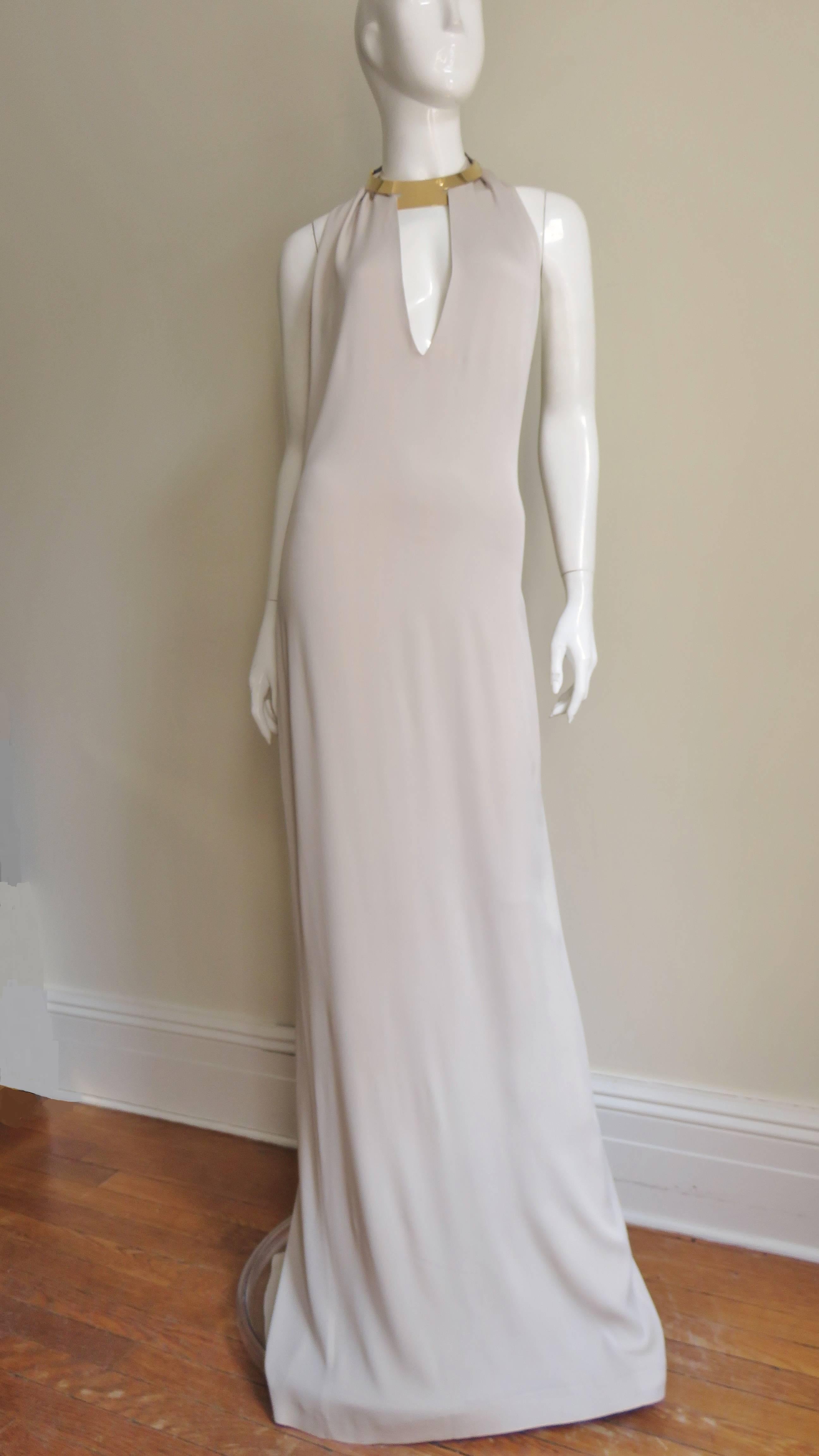 An absolutely gorgeous elegant light taupe colored silk jersey dress from Gucci.  It has a plunging keyhole cutout in the front and dips below the waist in the back.  The dress has a fabulous gold metal choker style attached collar with leather