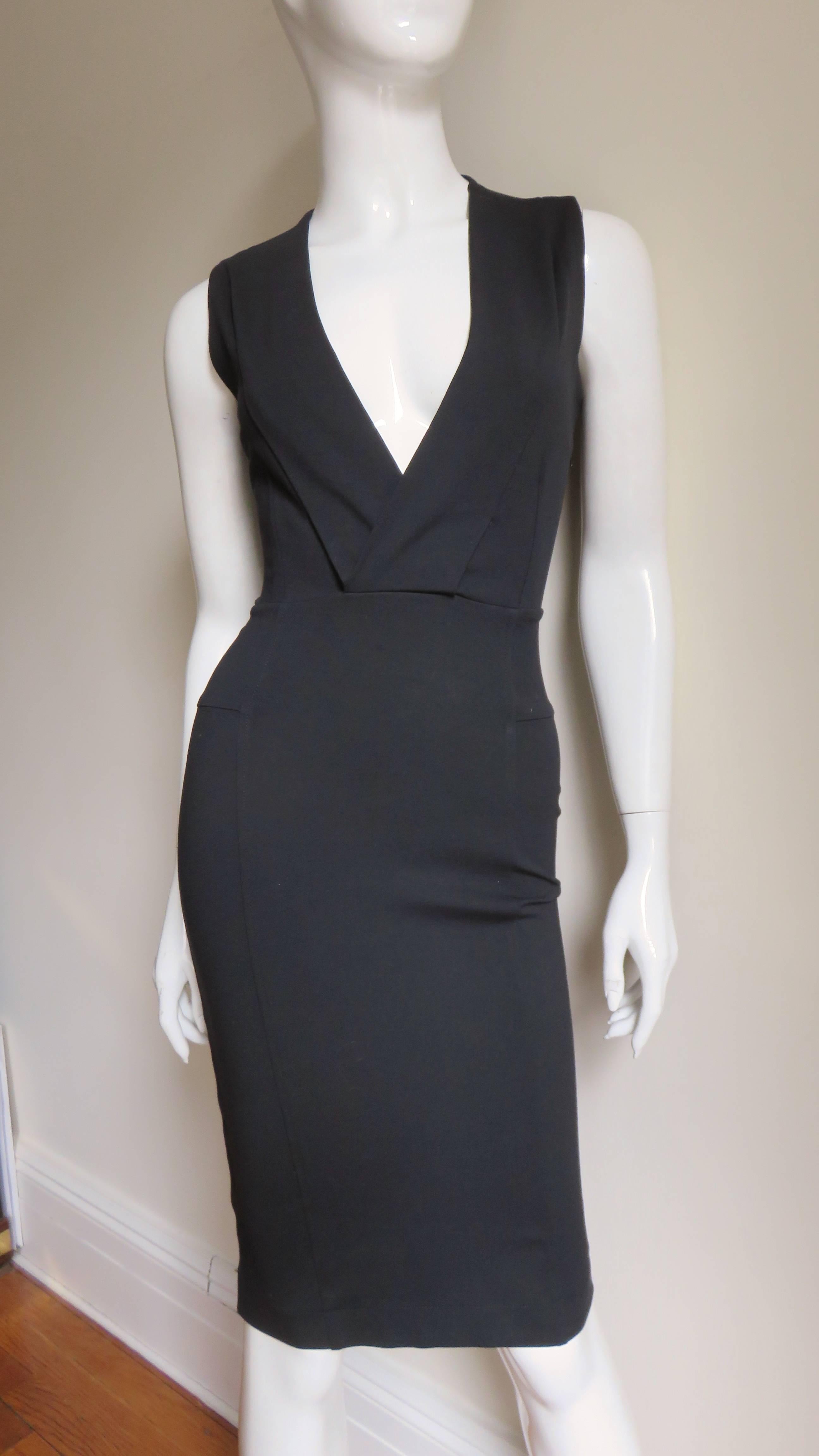 A great black stretch dress from Gucci.  It is sleeveless with a plunging neckline framed by 2 panels.   The waist and skirt are fitted and there is vertical seaming and paneling to create this.  It is unlined and has a side zipper.  
Fits sizes