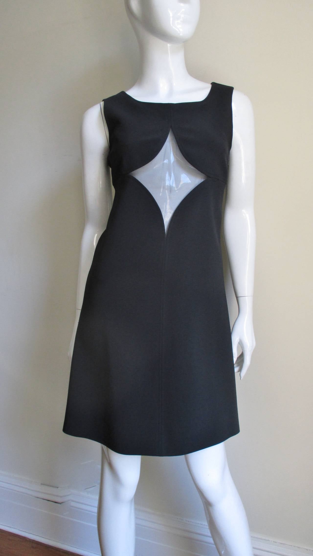 A simple sleeveless black jersey A line dress with a dramatic sheer covered cut out in the front and back from Courreges. It is fully lined and has a side zipper.  
Fits sizes Extra Small, Small, Medium.

Bust  34