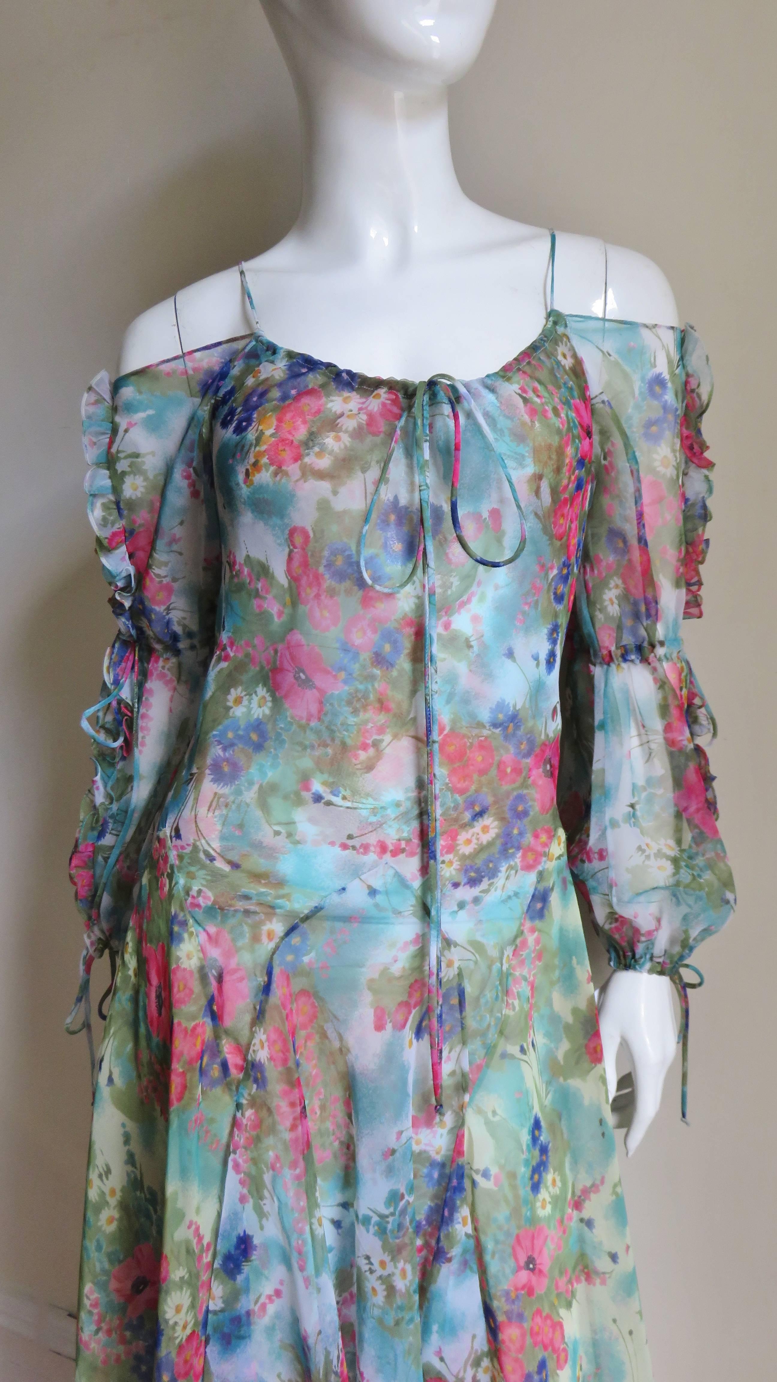 A feminine flower pattern silk dress from Giorgio Sant'Angelo in blues, reds, greens and white.  It has exposed shoulders with spaghetti straps, 2 cut outs along the sleeves and functional adjustable drawstrings above the elbows and at the wrists.