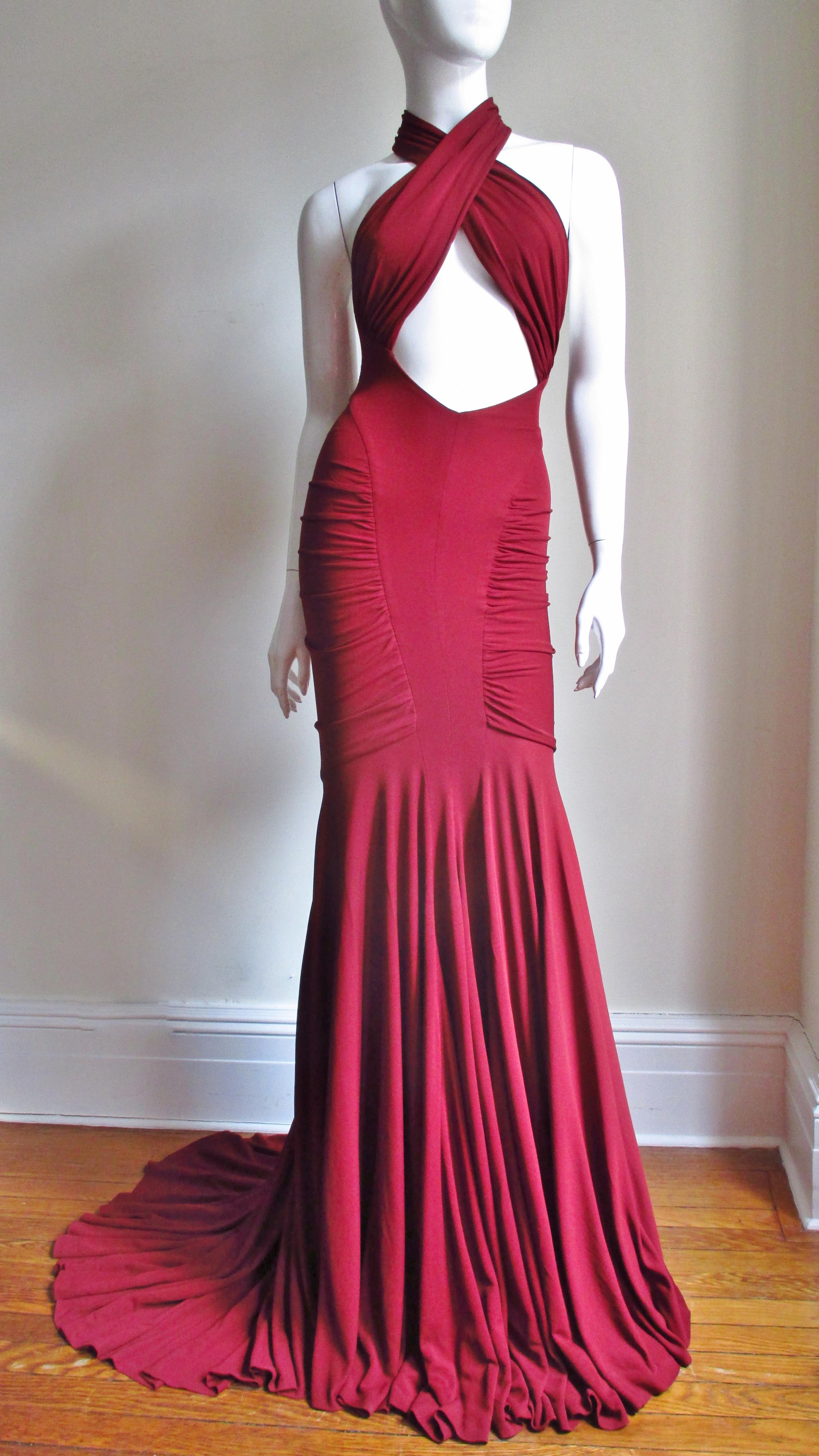 An absolutely stunning gown by Herve Leger for Guy Laroche 2005 Collection with all of the attention to the body conscious fit he is famous for. It is an incredible design in burgundy red silk jersey with a wrap, cross ruched front bodice leaving a